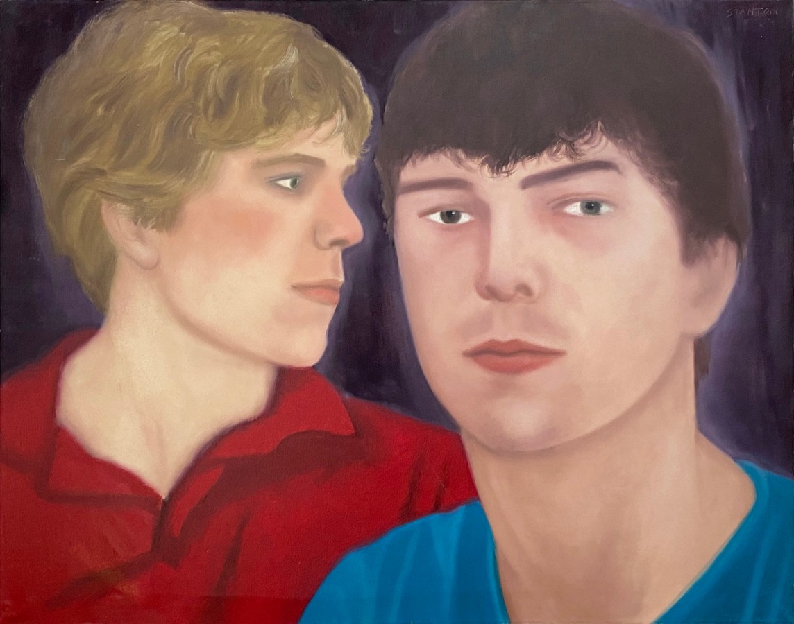 close up portrait of a blonde man seen in profile in a red polo shirt and a brunette man in a blue t-shirt