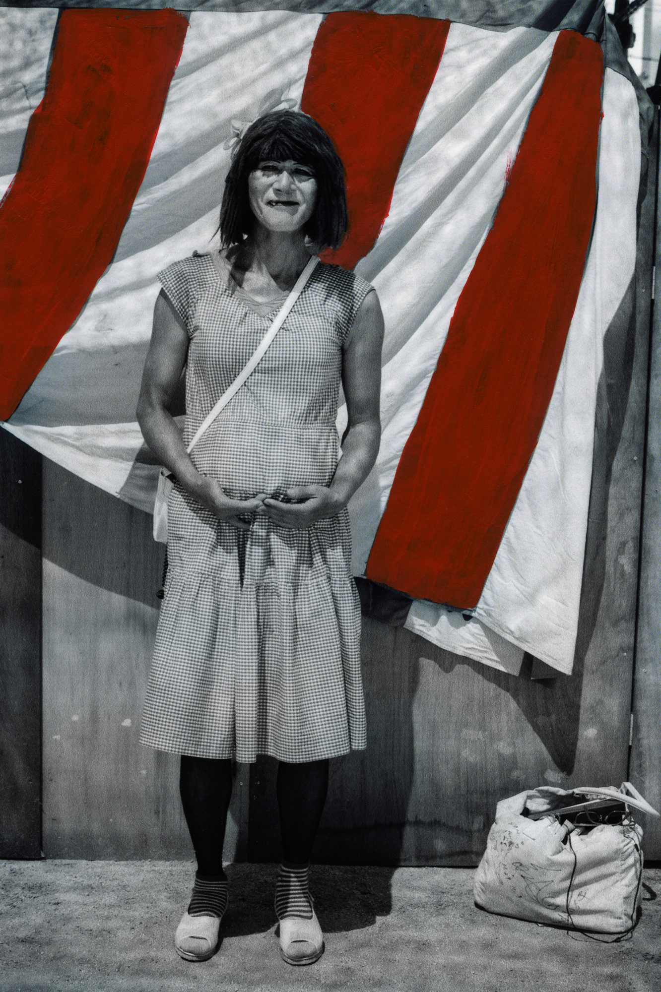 black-and-white image of a woman standing in front of a red and white striped flag