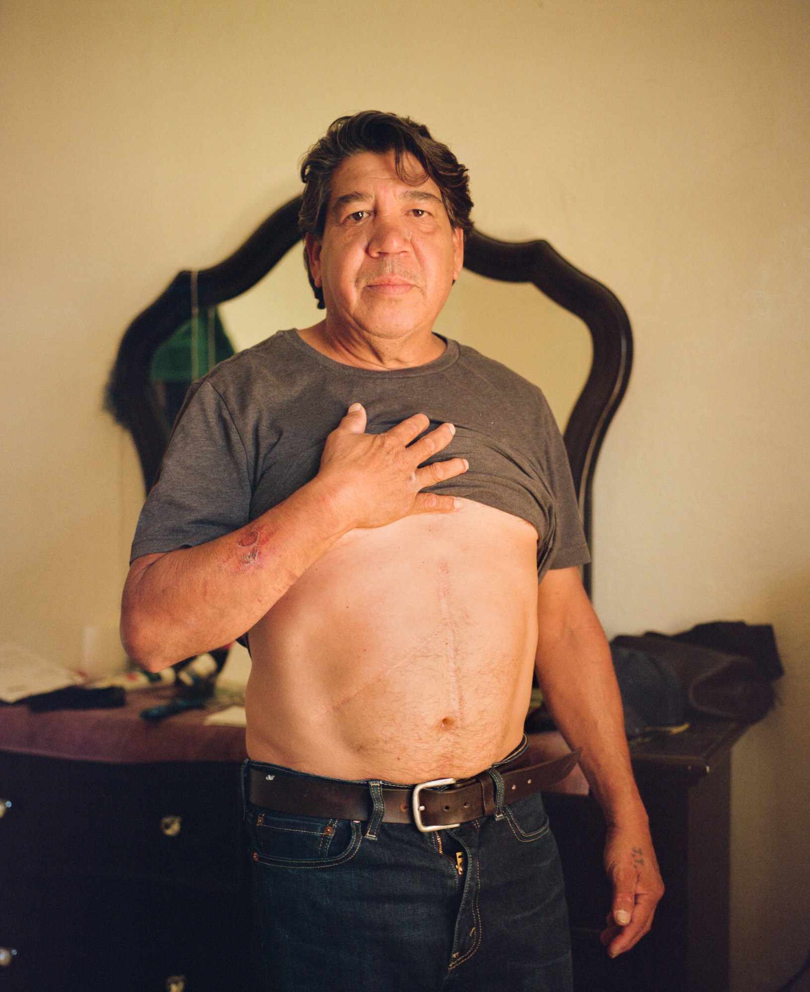 a man holding up his shirt with his hand on his chest