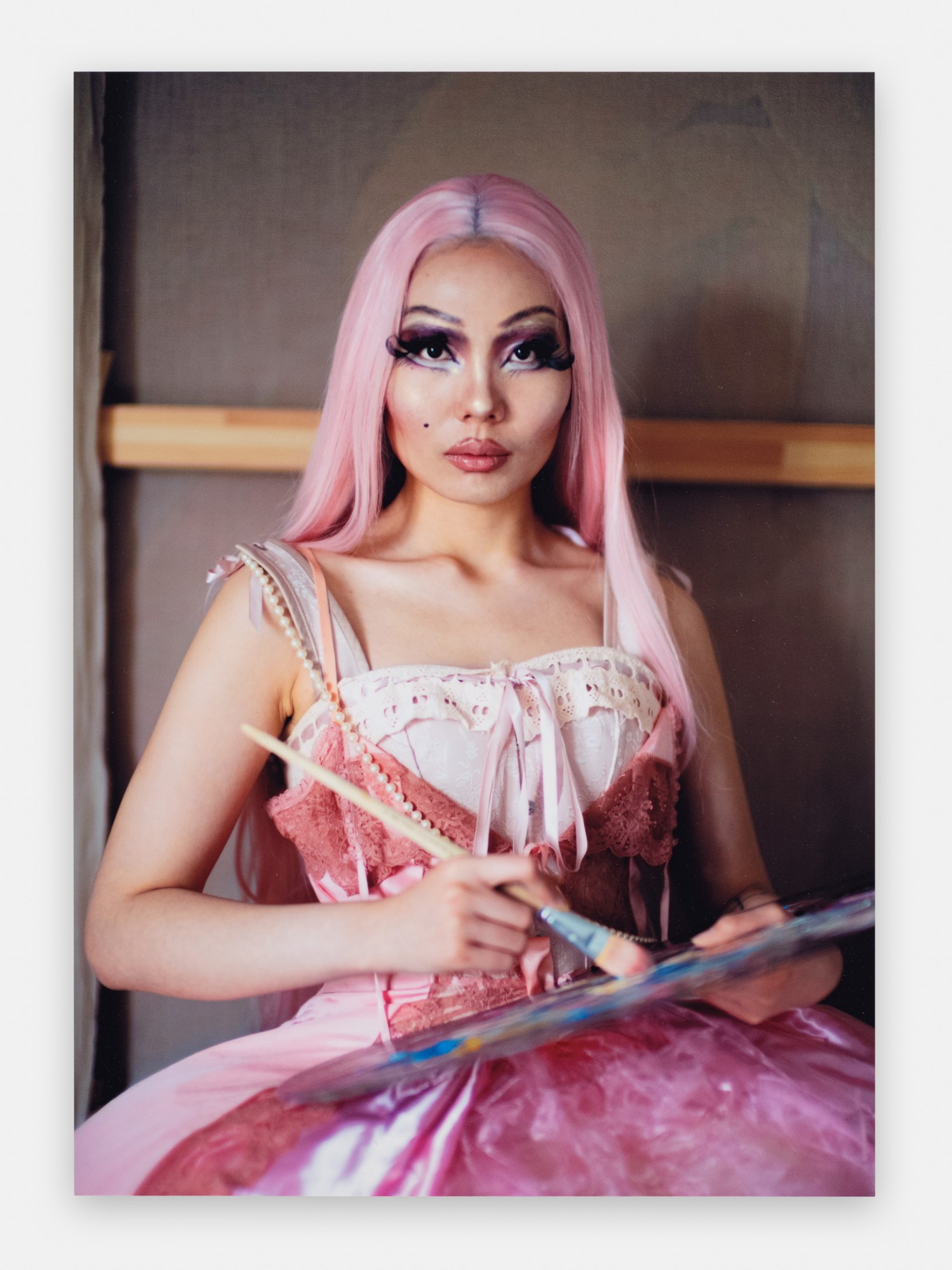 a woman in a pink wig and dress holding a palette and paintbrush