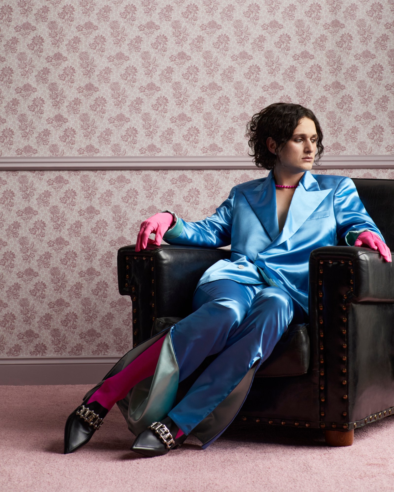 Jocelyn of Walt Disco wearing a silk blue suit and pink gloves and tights and black leather loafer-style with silver chain on the front louboutin heels