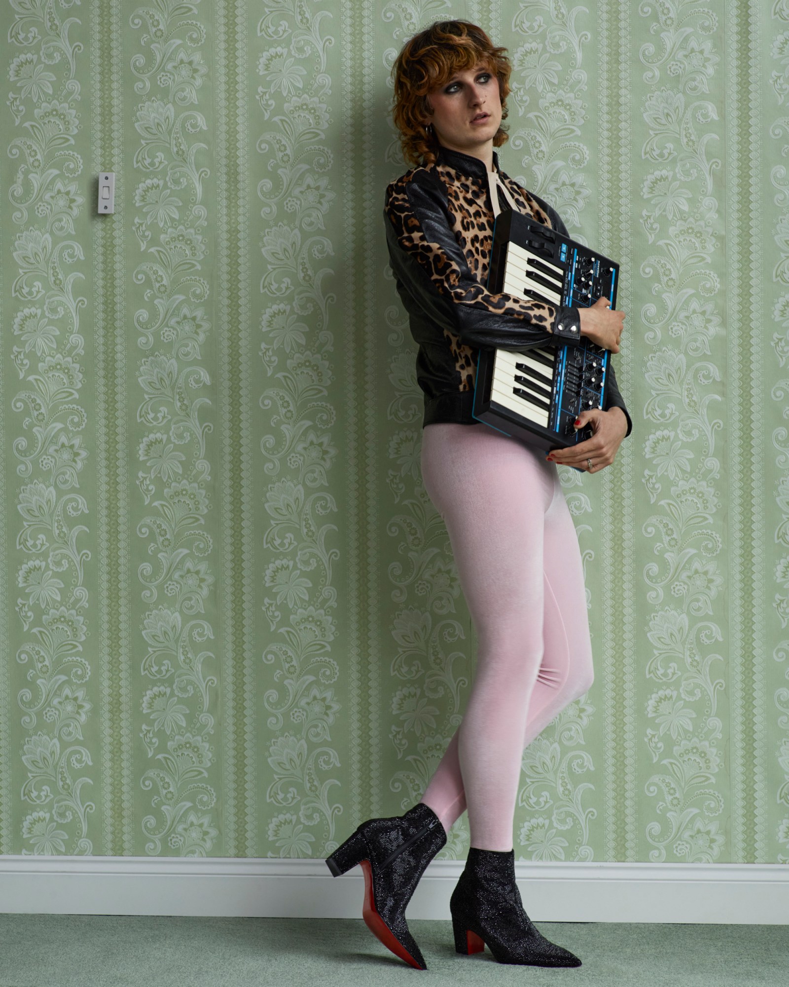 Finlay of Walt Disco wearing baby pink velvet leggings, a leopard print bomber jacket and black sparkling boots with a keyboard