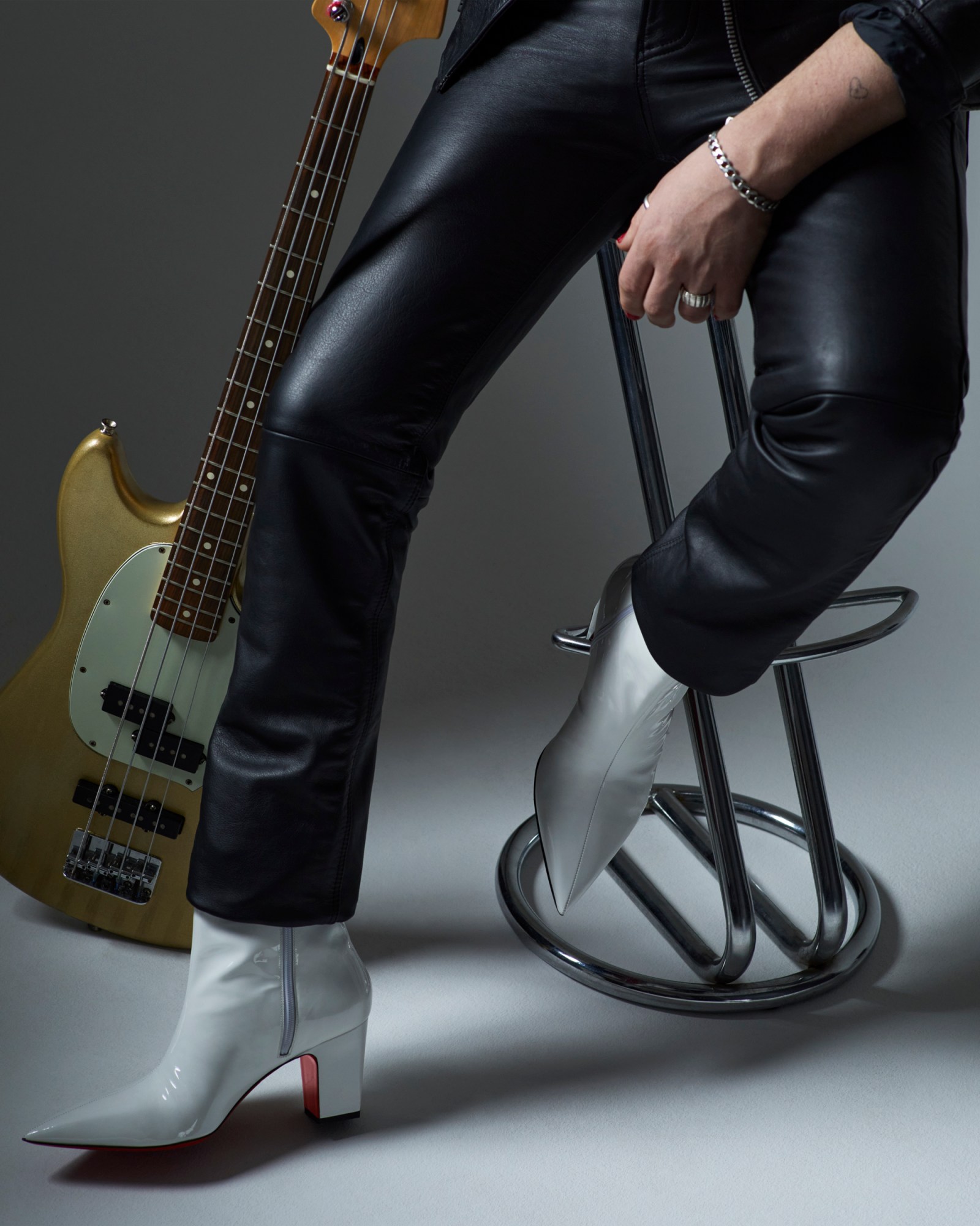 Charlie of Walt Disco wearing leather trousers and white louboutin boots and holding a guitar