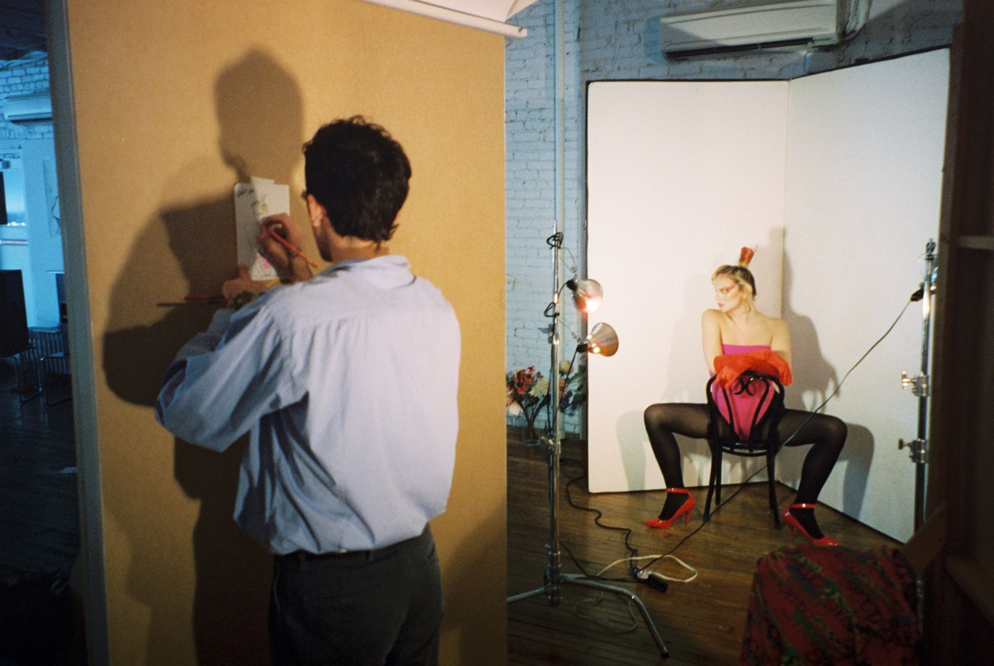 the artist drake carr drawing a sketch of a model sitting on a chair in black tights and pink swimsuit