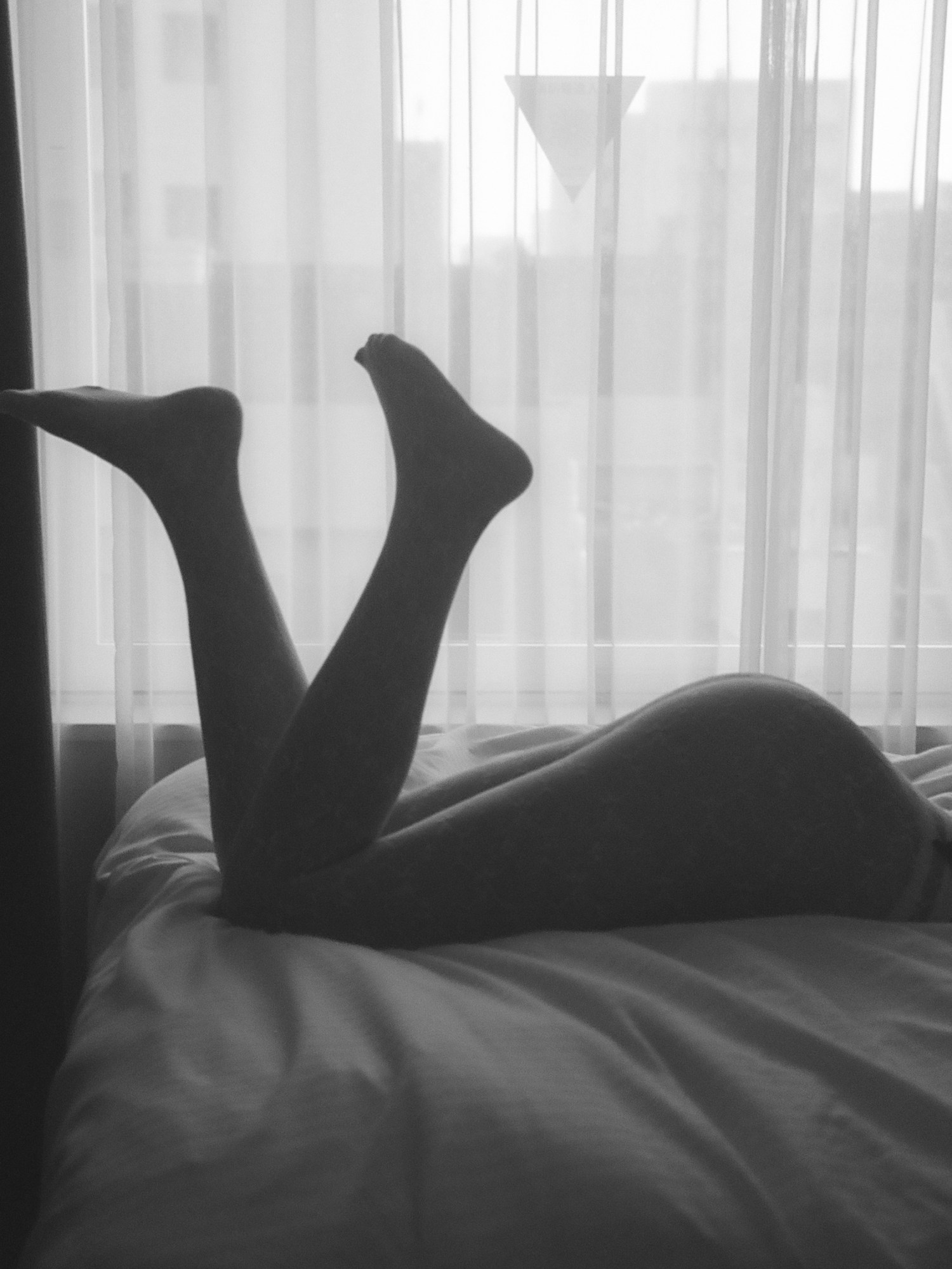 silhouette of a girl lying on a bed with her feet up