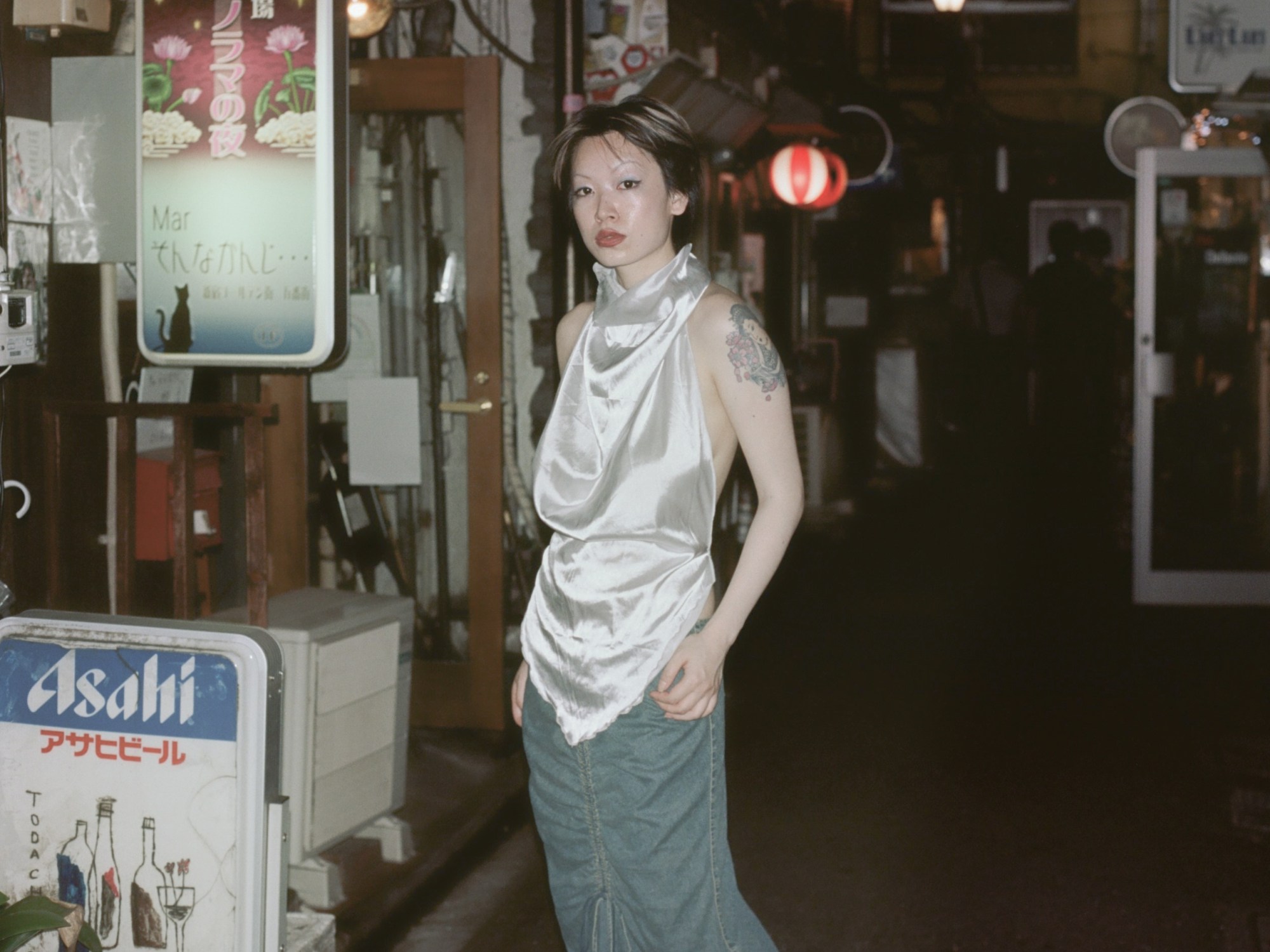 a girl wearing a silver top in tokyo standing in the middle of a market