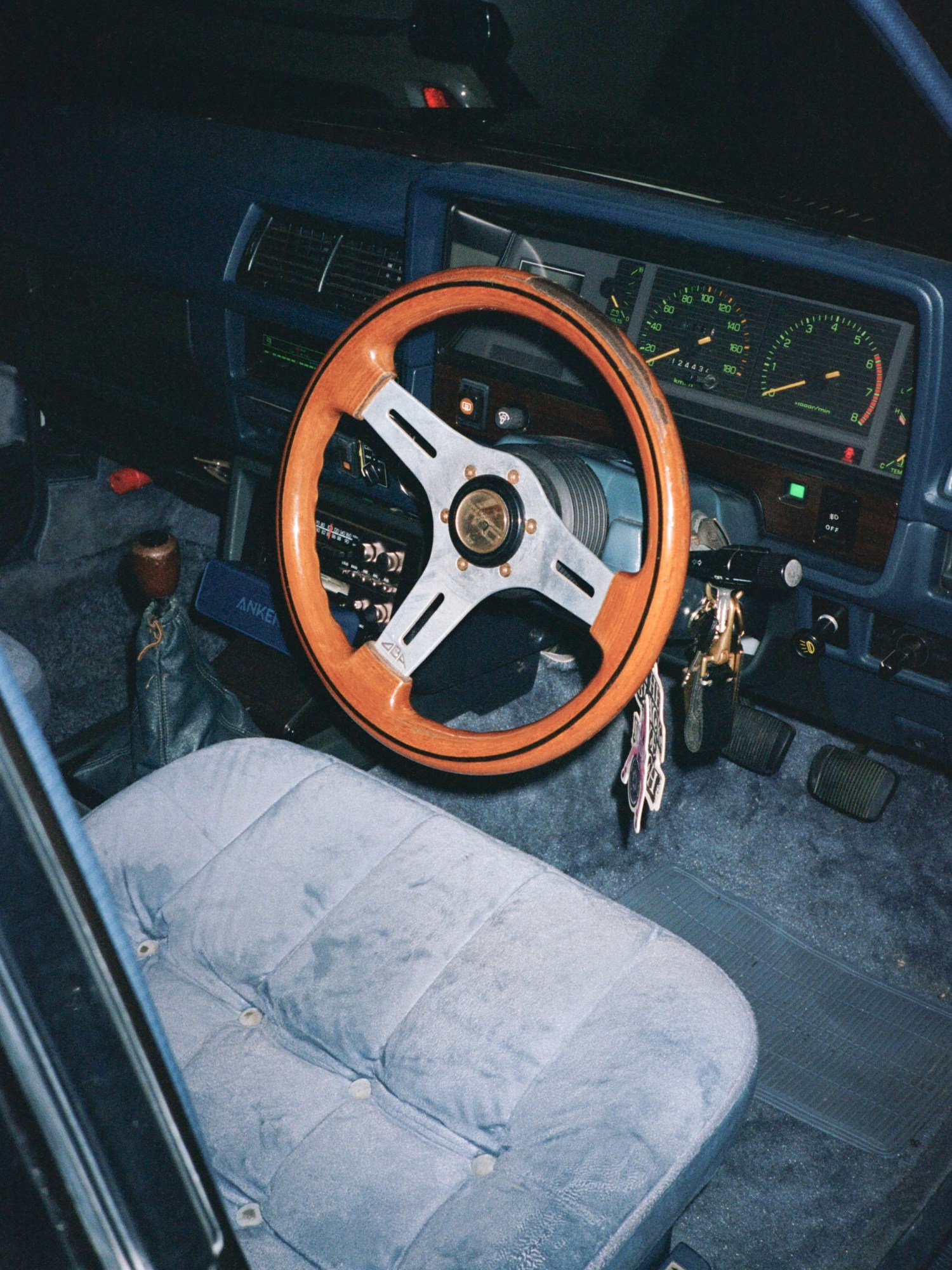 close up of an antique wooden stearing wheel in a blue upholstered car