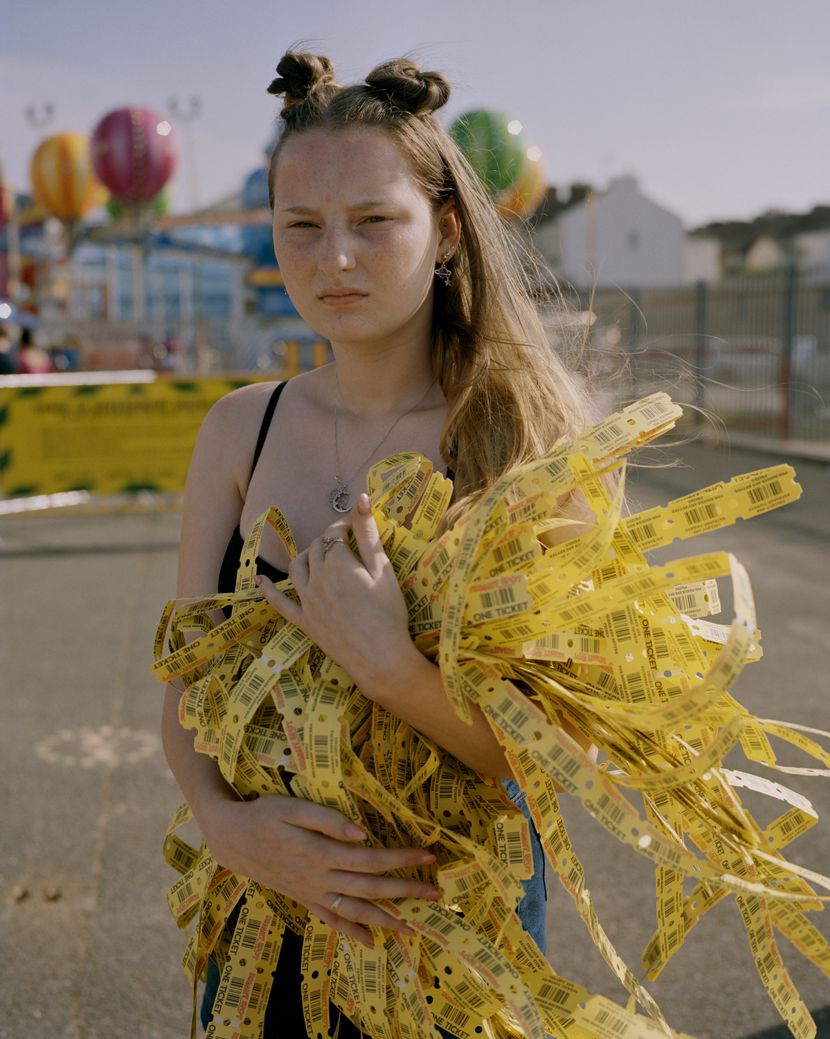 a girl holding a bunch of yellow arcade tickets in her arms