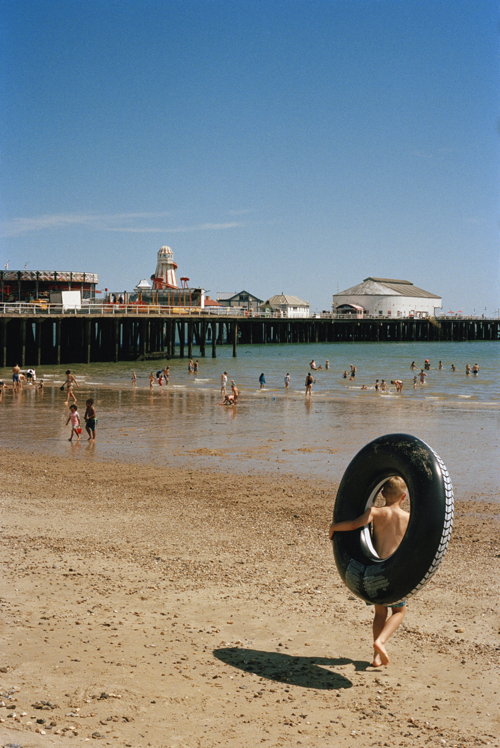 a boy running into the ocean holding a round tire float