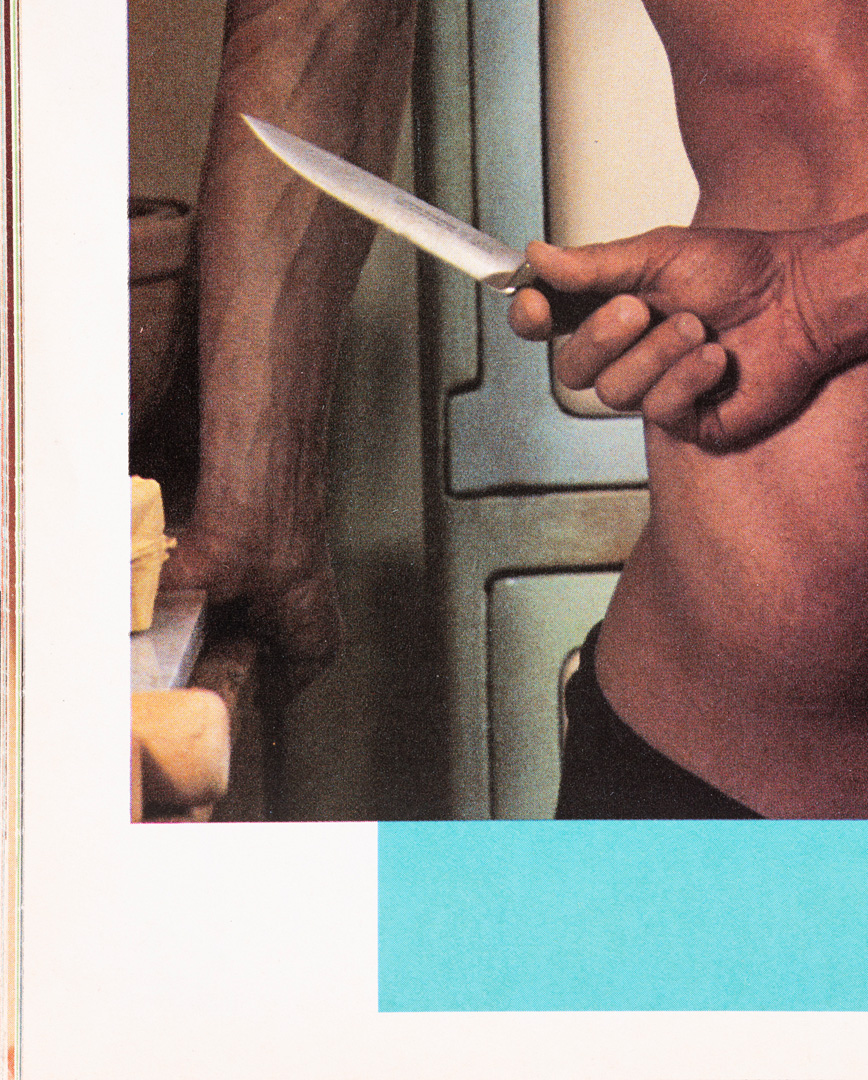 a crop of a topless muscular man holding a knife, leaning on a kitchen counter