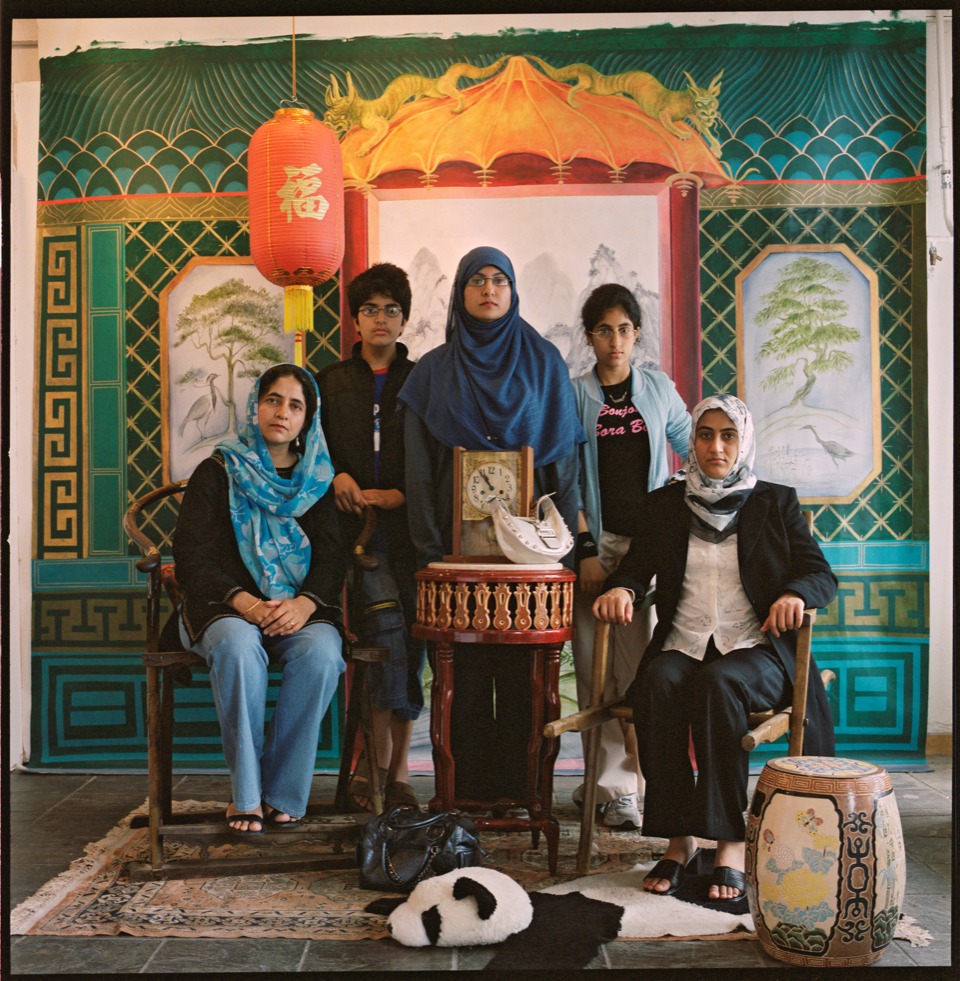 a group of 5 people resembling a family pose in the studio - 3 are wearing headscarves and two leather handbags are also in shot