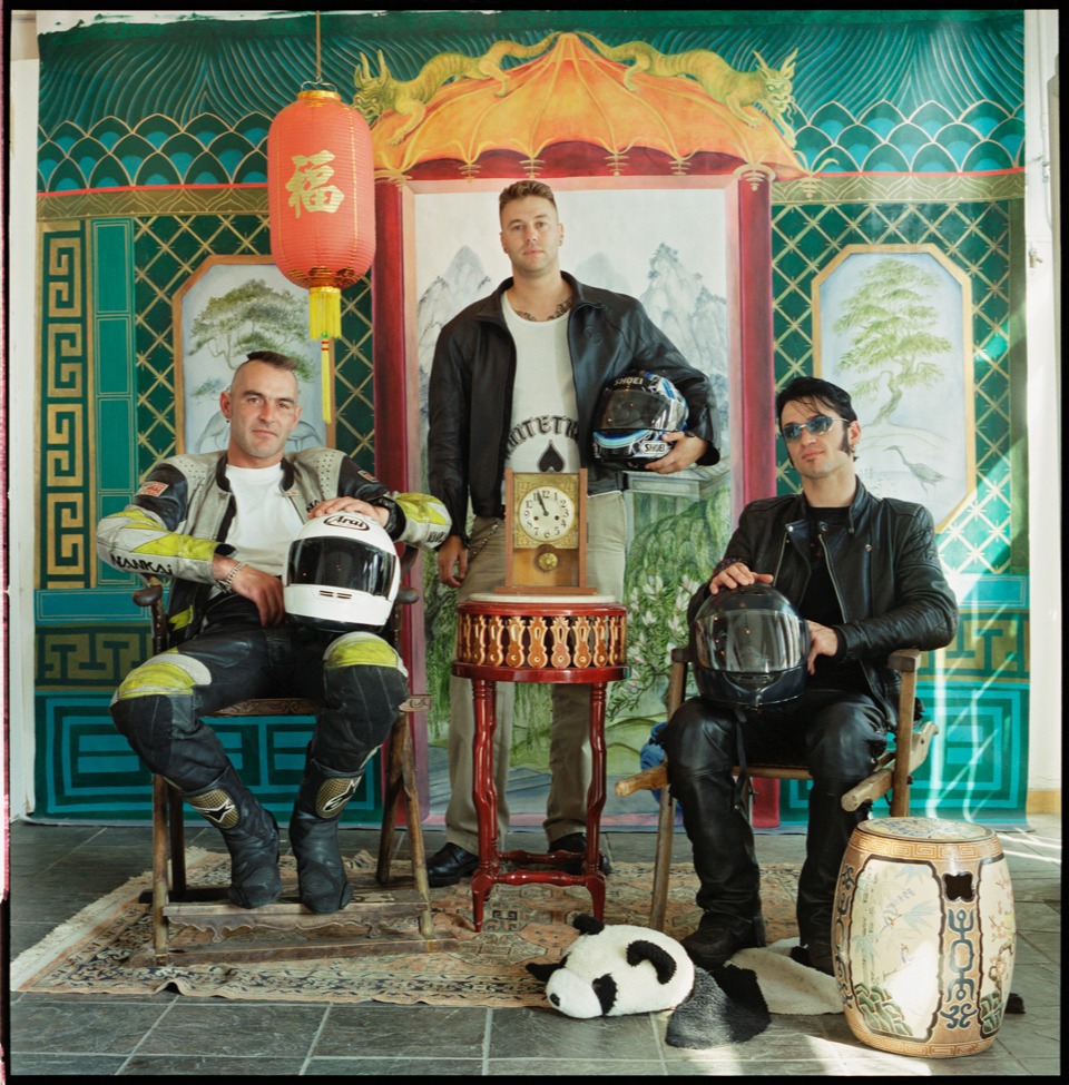 3 bikers pose in the studio with their motorcycle helmets wearing leather gear