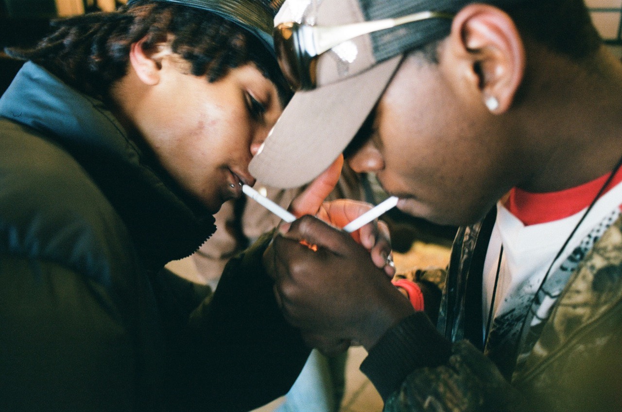 two friends cup their hands together to light their cigarettes