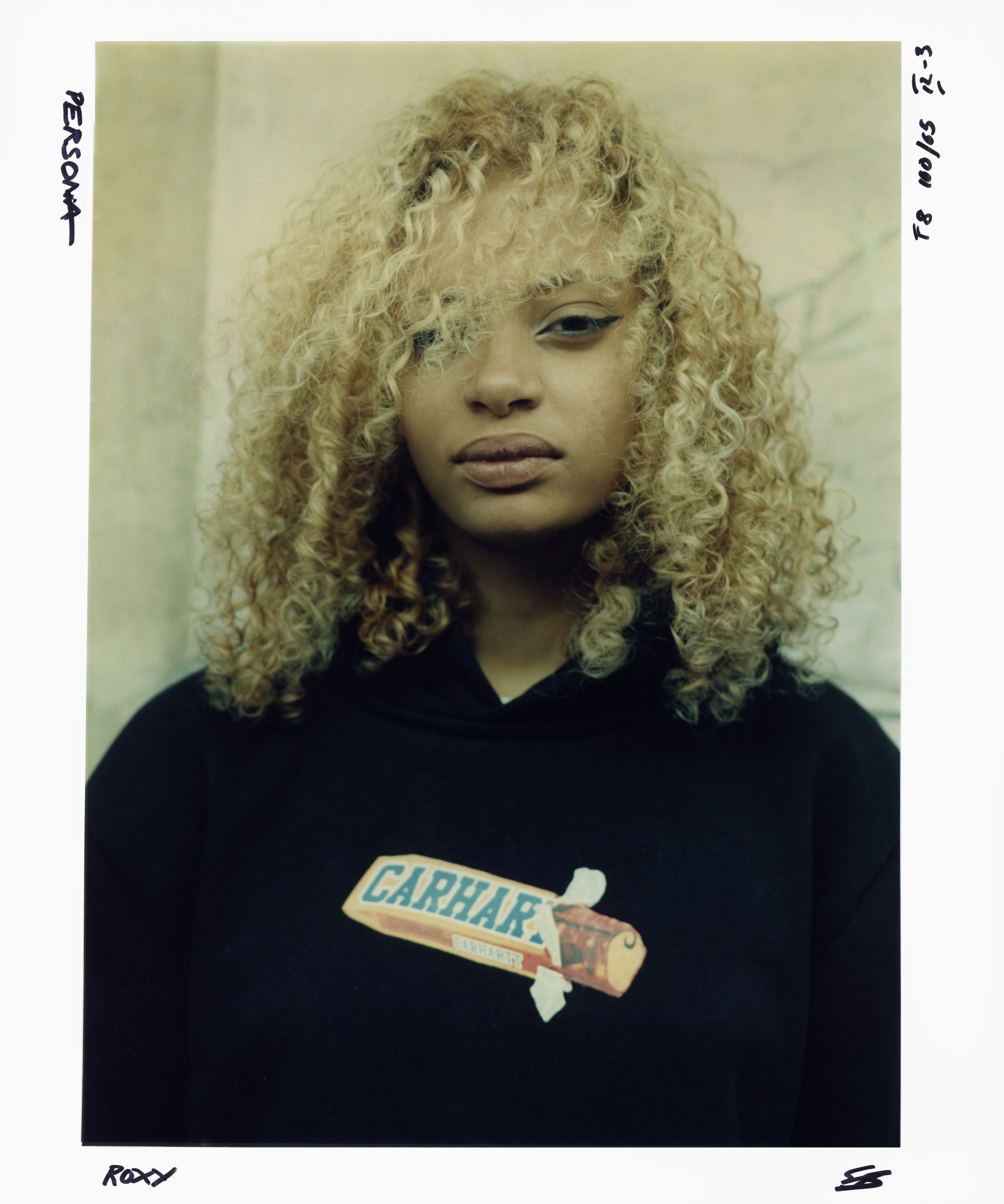 image of a person with curly blonde hair in a carhartt chocolate bar black hoodie