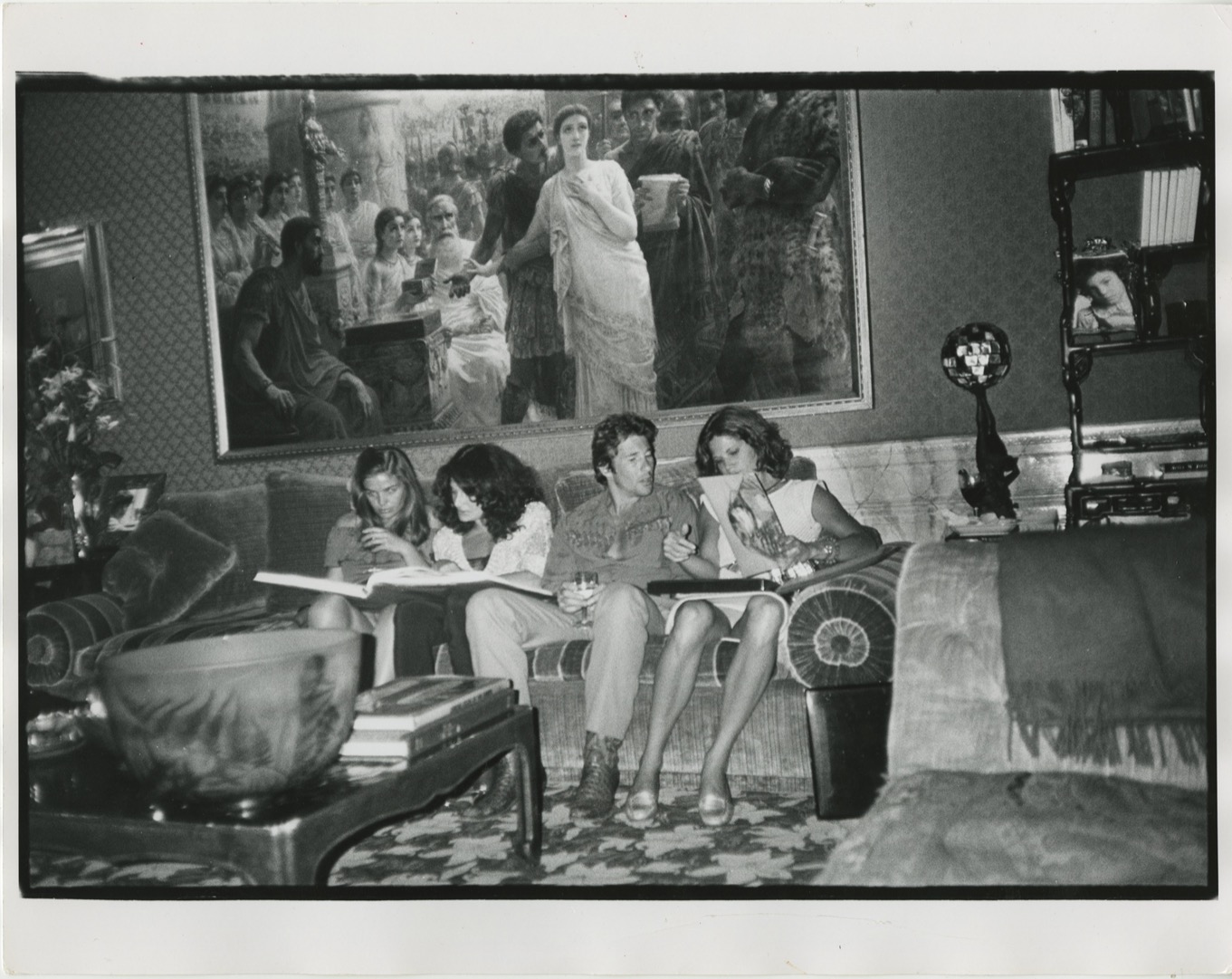 a group of people, including a young richard gere, sit on a velvet sofa in an opulent apartment