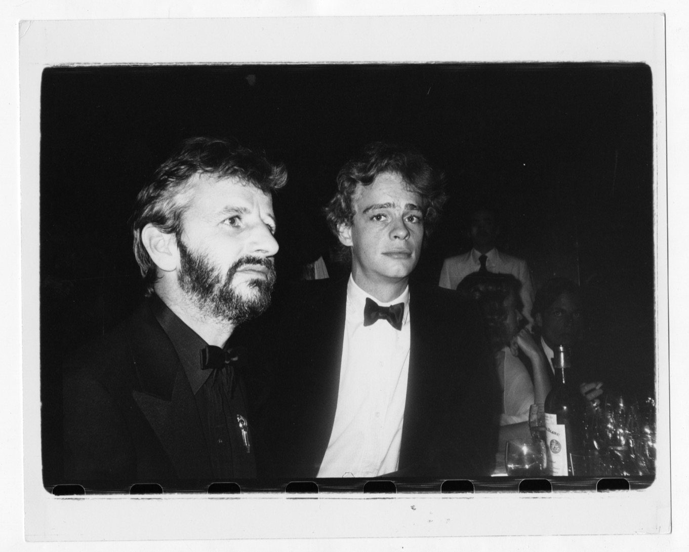 two men in suits with bowties stand at a bar