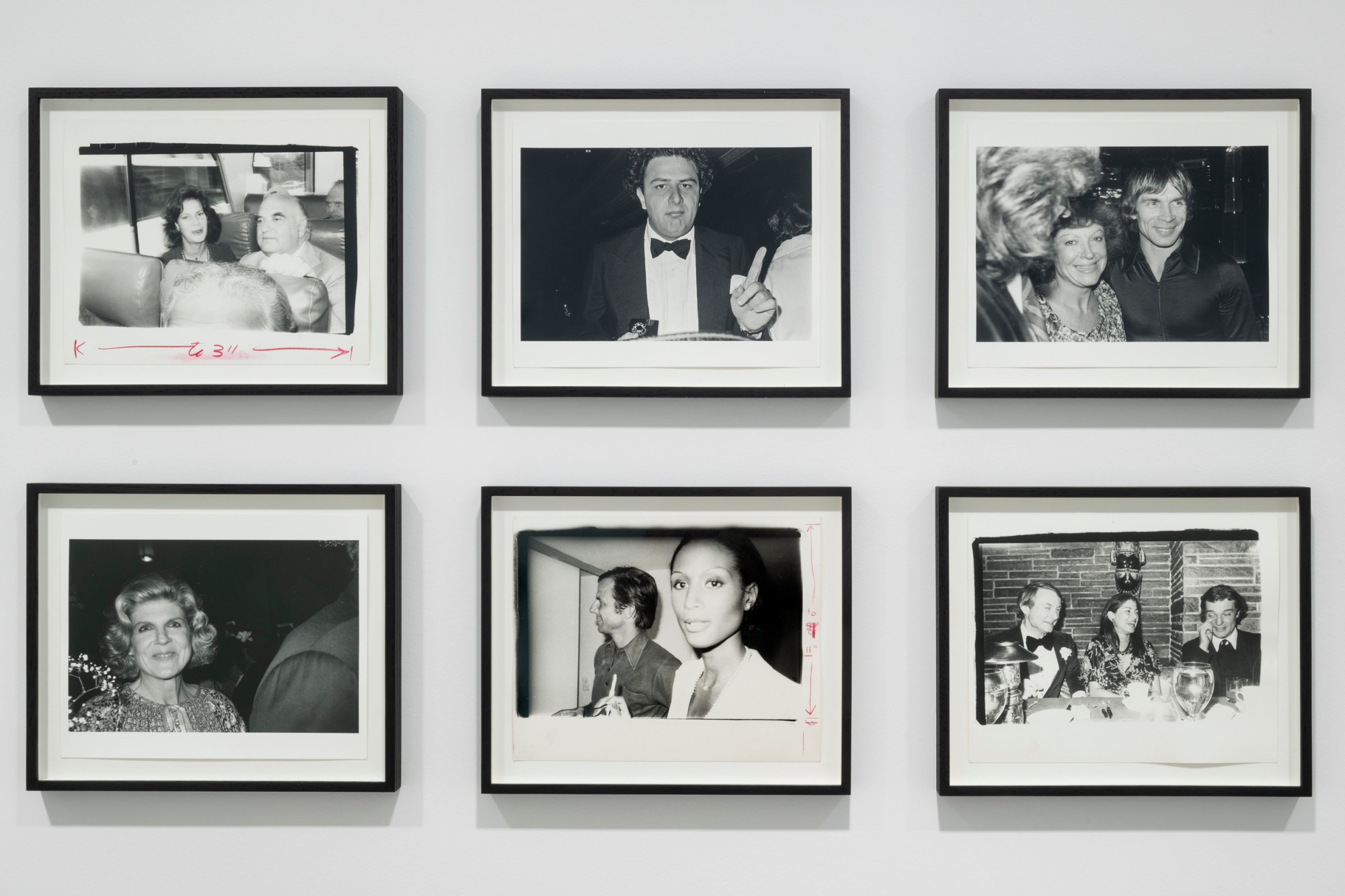 6 framed black and white photographs of people at parties and dinners on a gallery wall