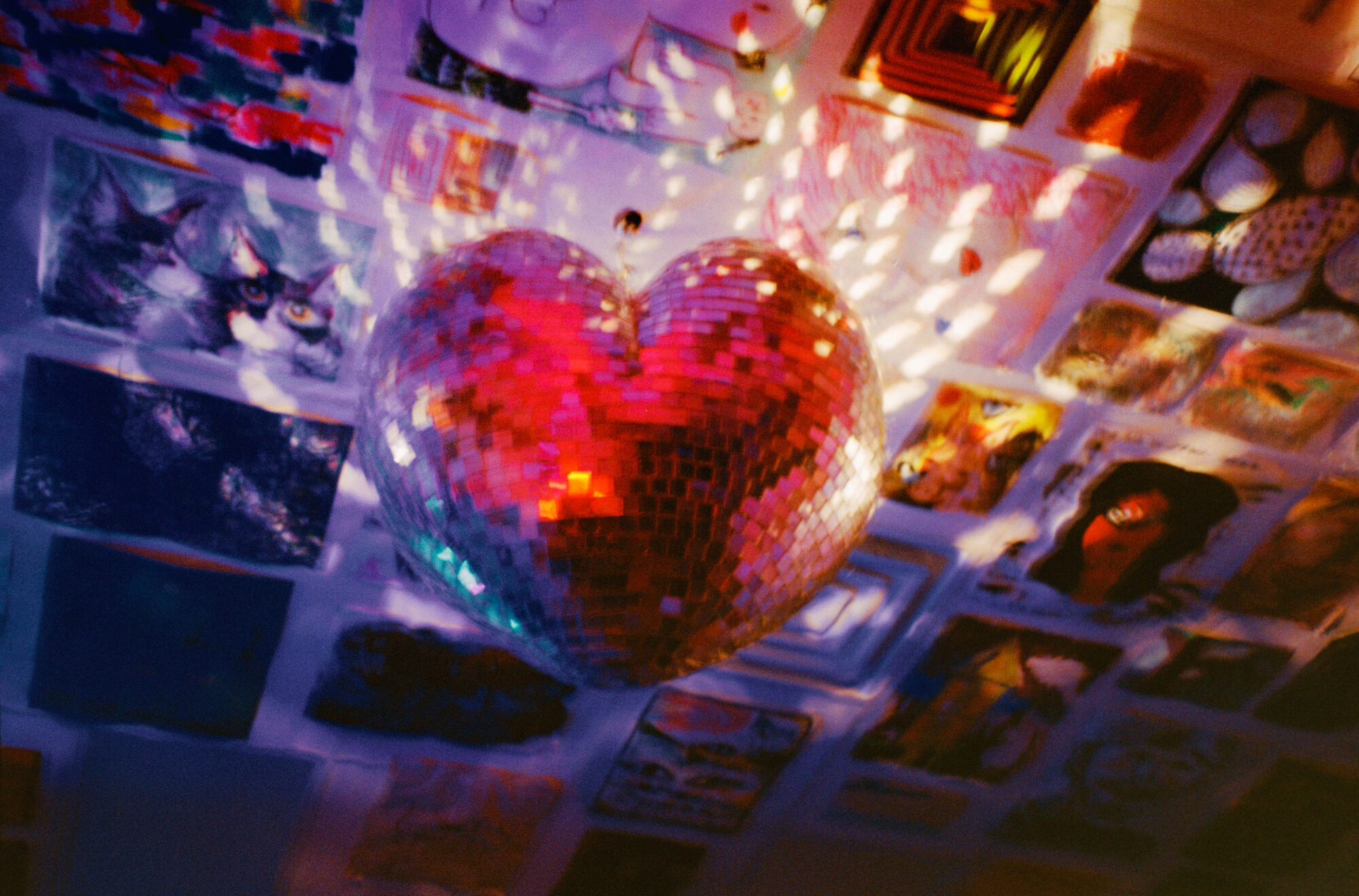 a heart shaped disco ball on the ceiling with photos surrounding it