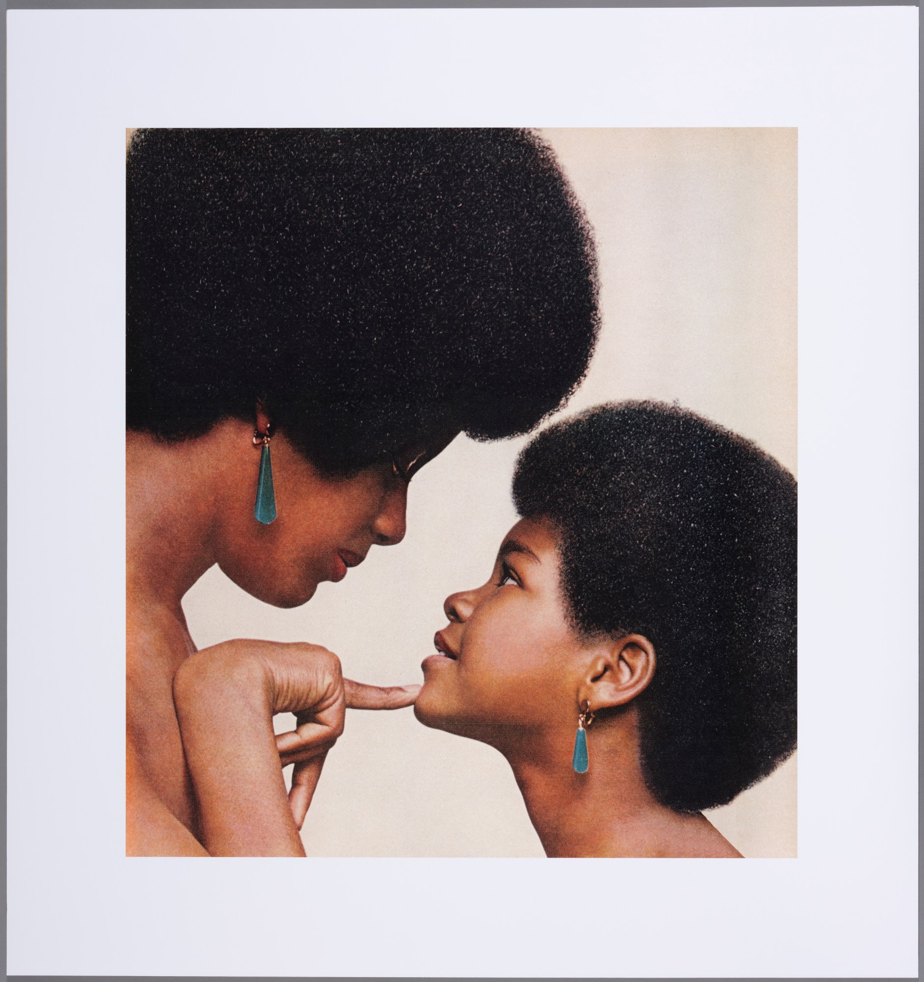 A Black mother and child with afros wearing turquoise earrings.