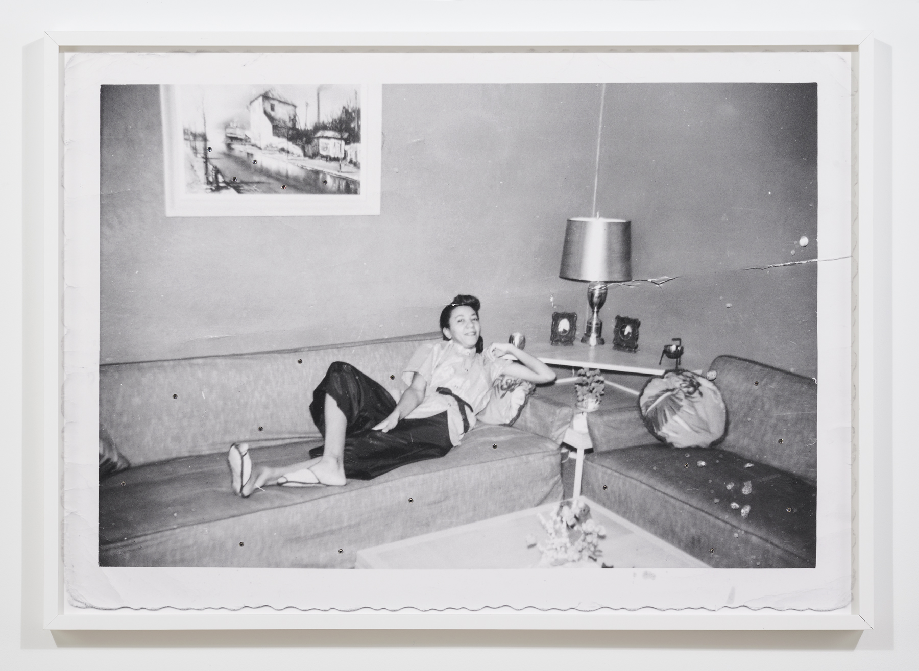 A photography from the 50s of woman sitting in a living room with mid century furniture.