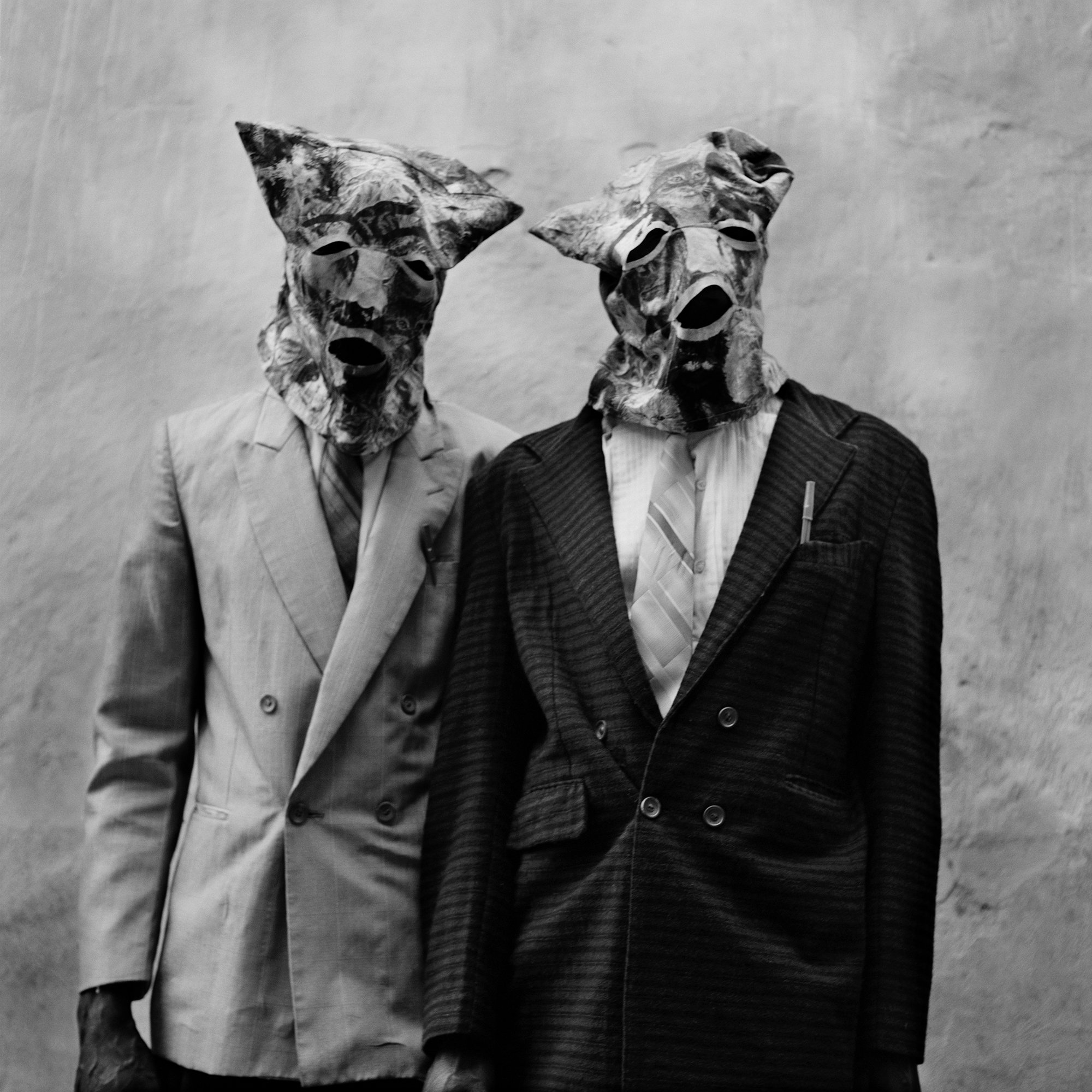 Two men wearing suits and cloth masks.