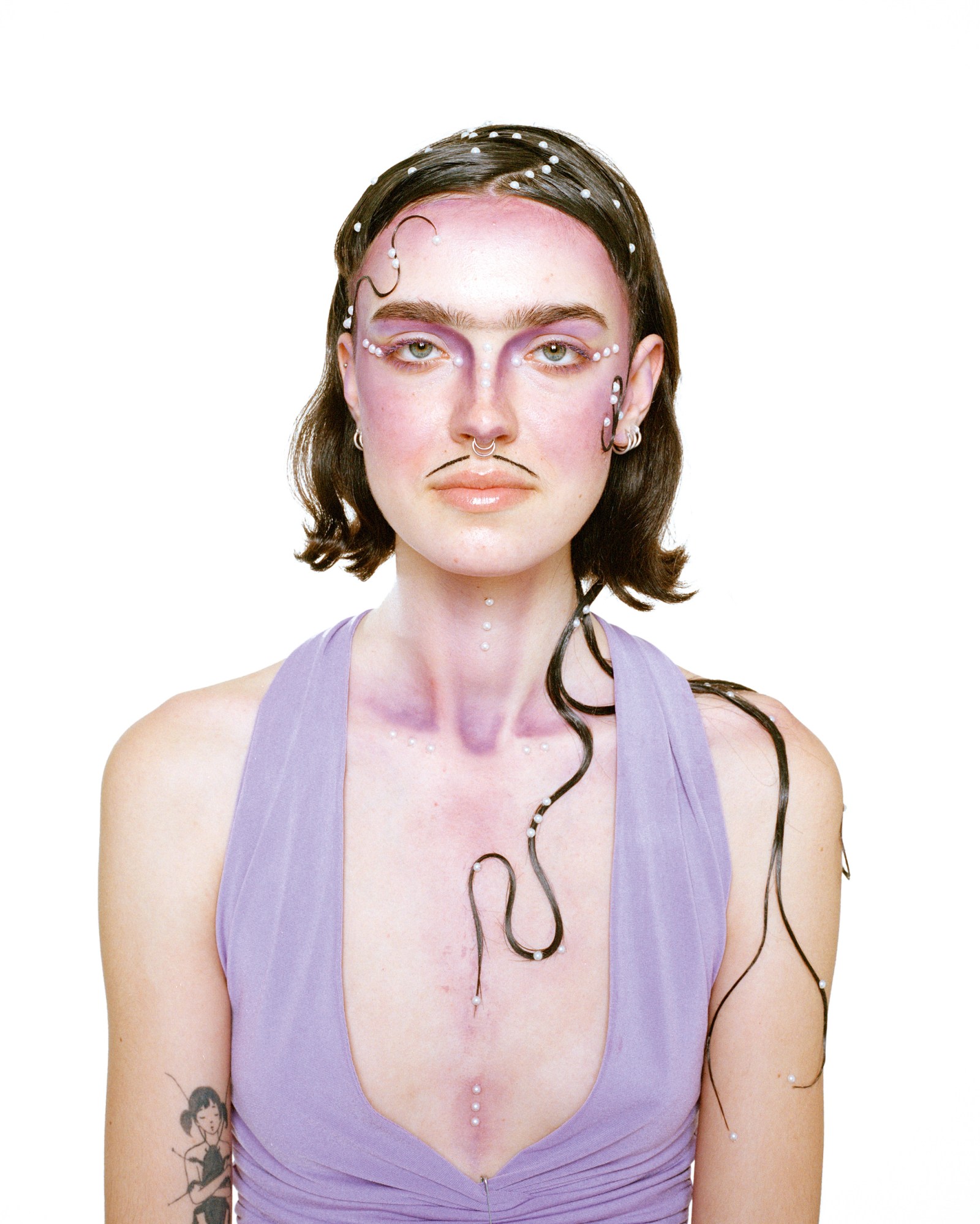 a person with costume-like purple makeup and drawn-on moustache wears a lilac top and an intricate hairstyle