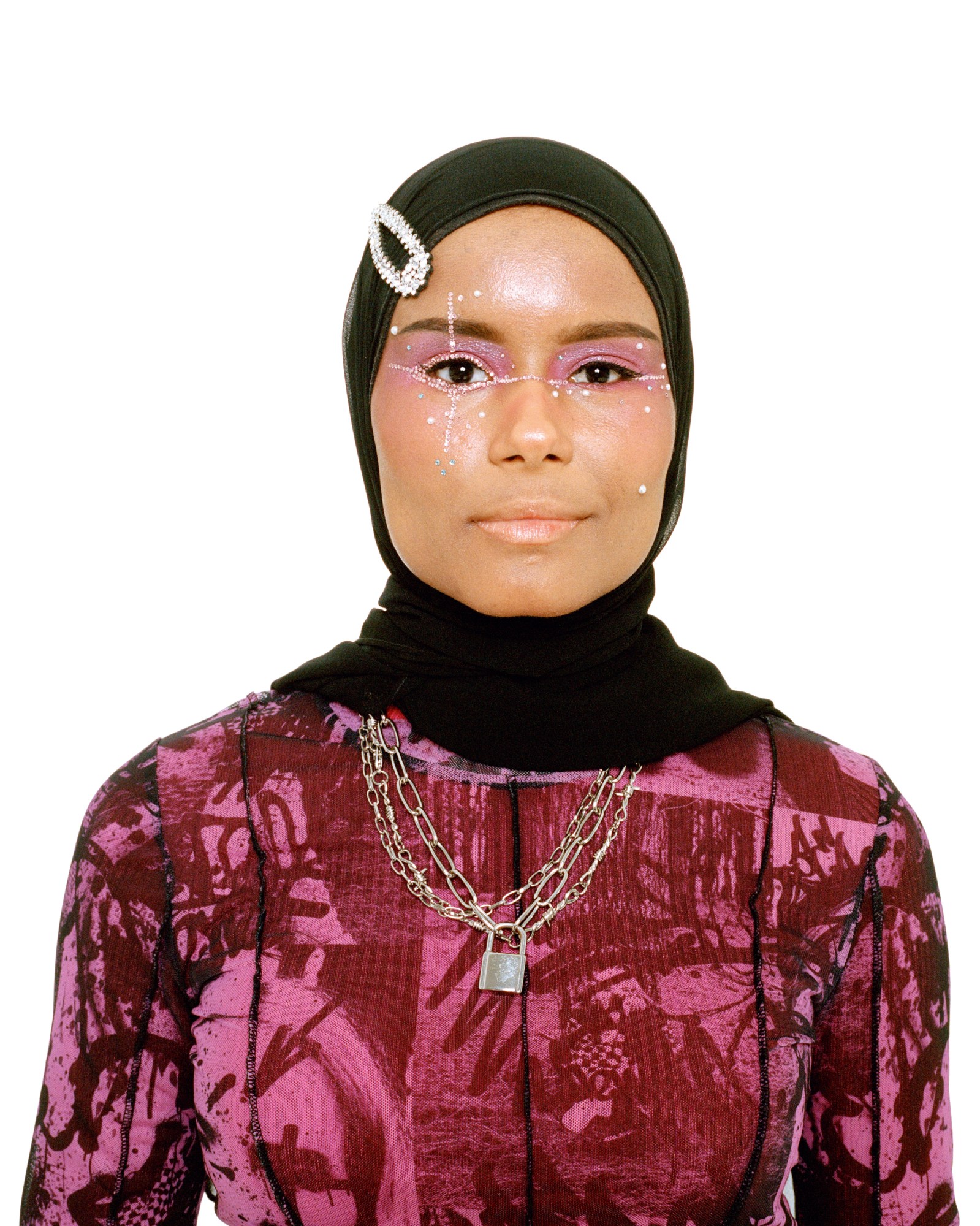 a young muslim woman wearing glitter eye makeup, chain necklaces and a headscarf