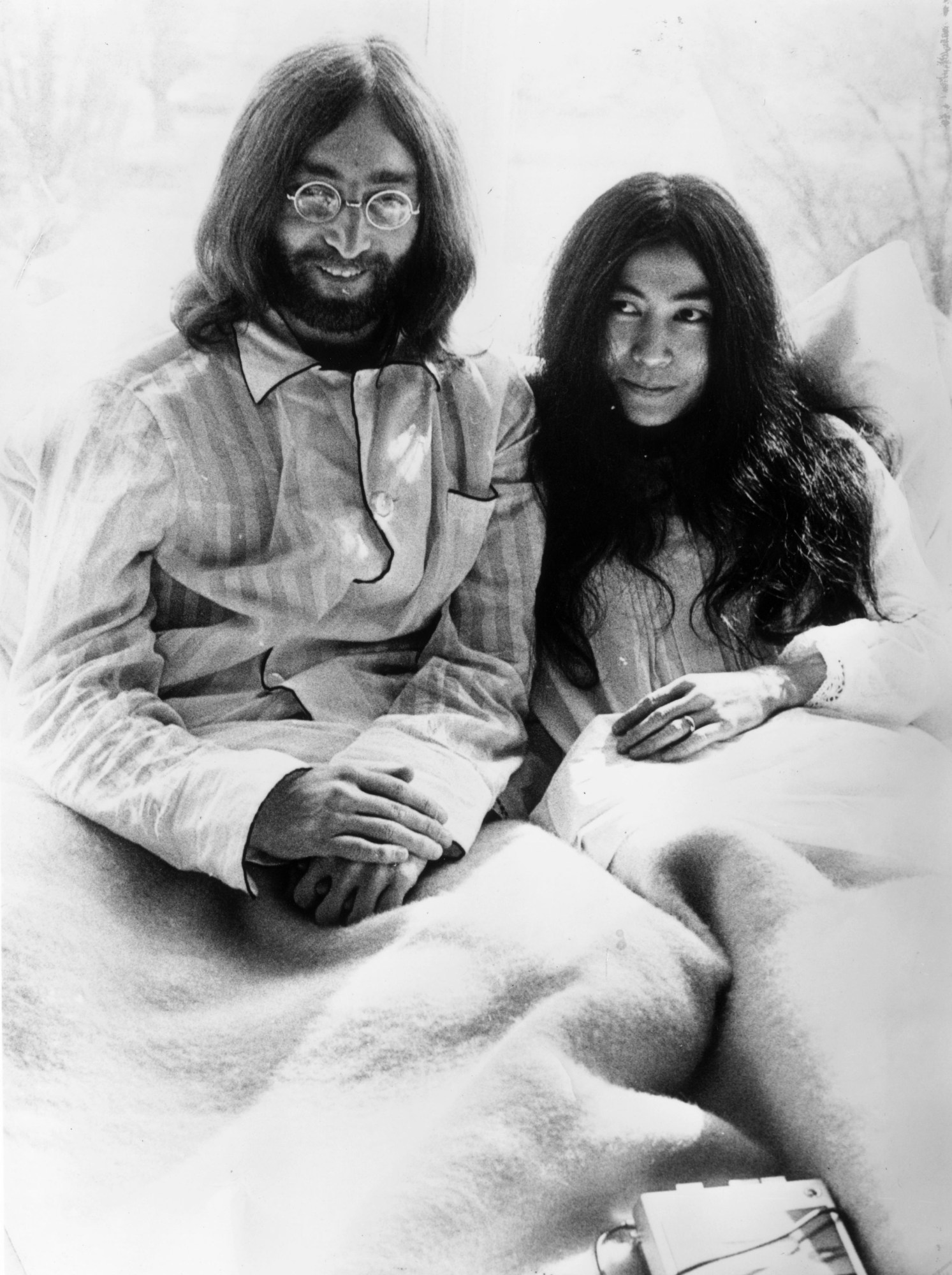 john lennon and yoko ono wearing pyjamas in bed for their bed-in protest on their honeymoon