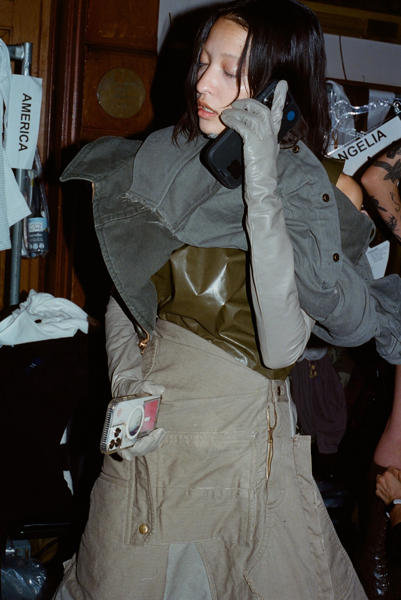 a model talks on the phone while holding a phone backstage at marc jacobs AW23