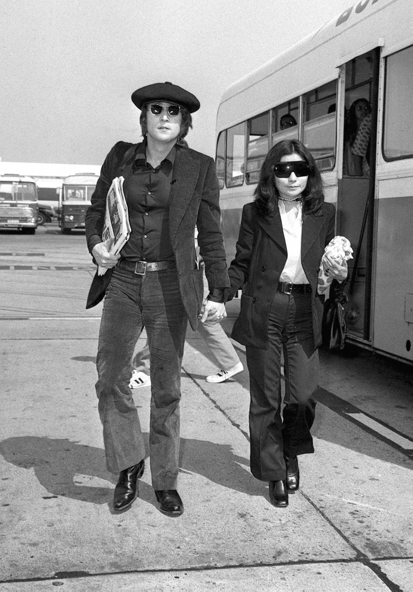 john lennon and yoko ono getting off a bus on the tarmac of a london airport in the 60s