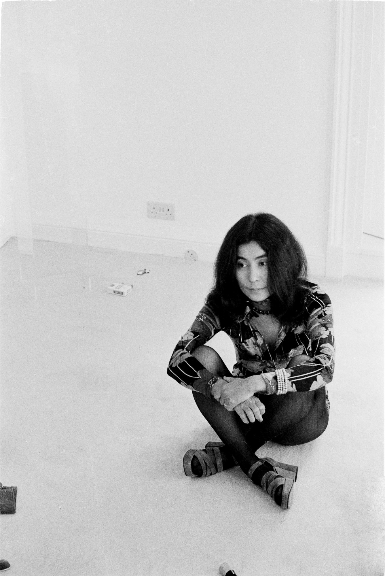 yoko ono sitting on the floor of her home wearing a pair of high heeled shoes