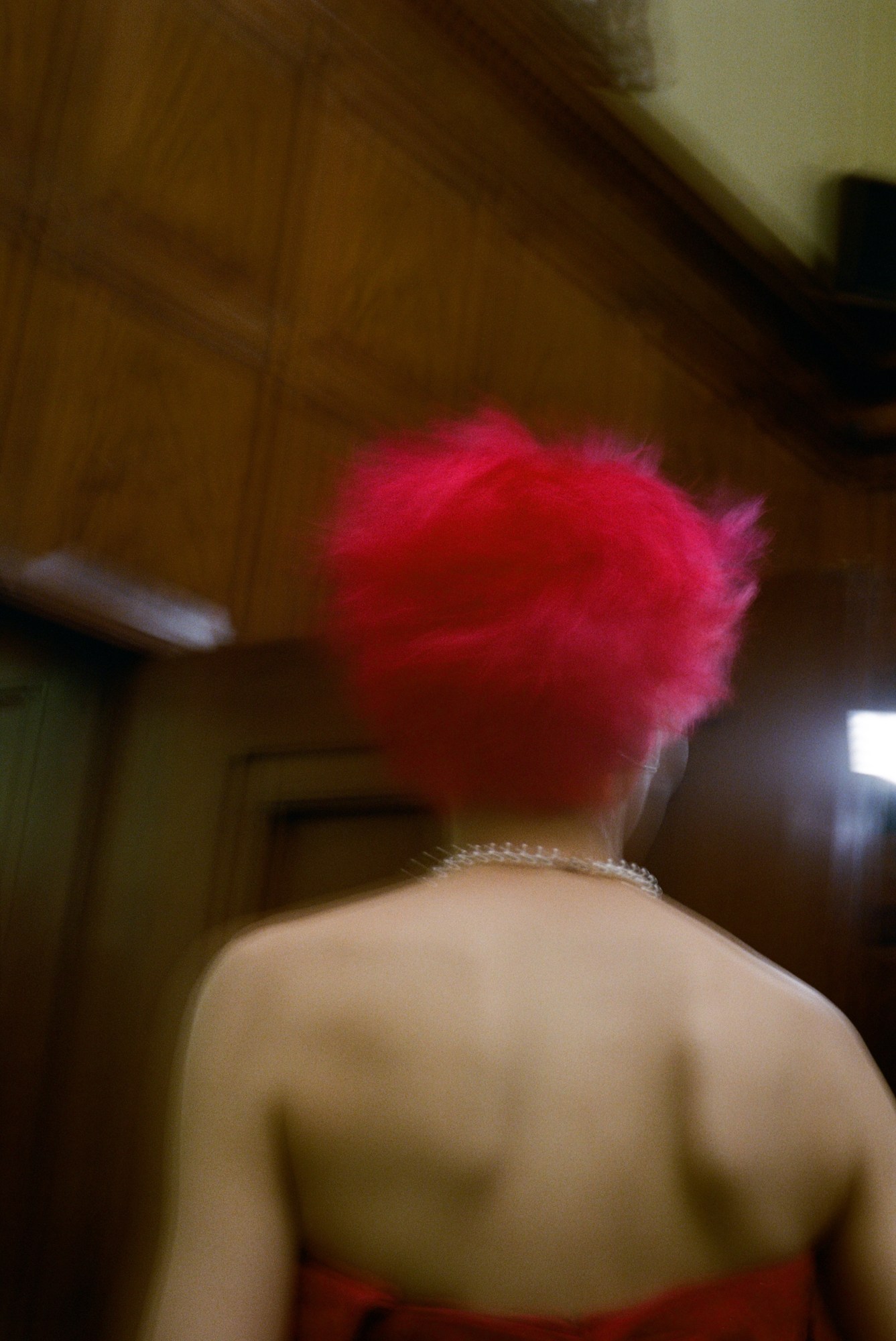 blurry image of a pink haired model shot from behind backstage at marc jacobs aw23