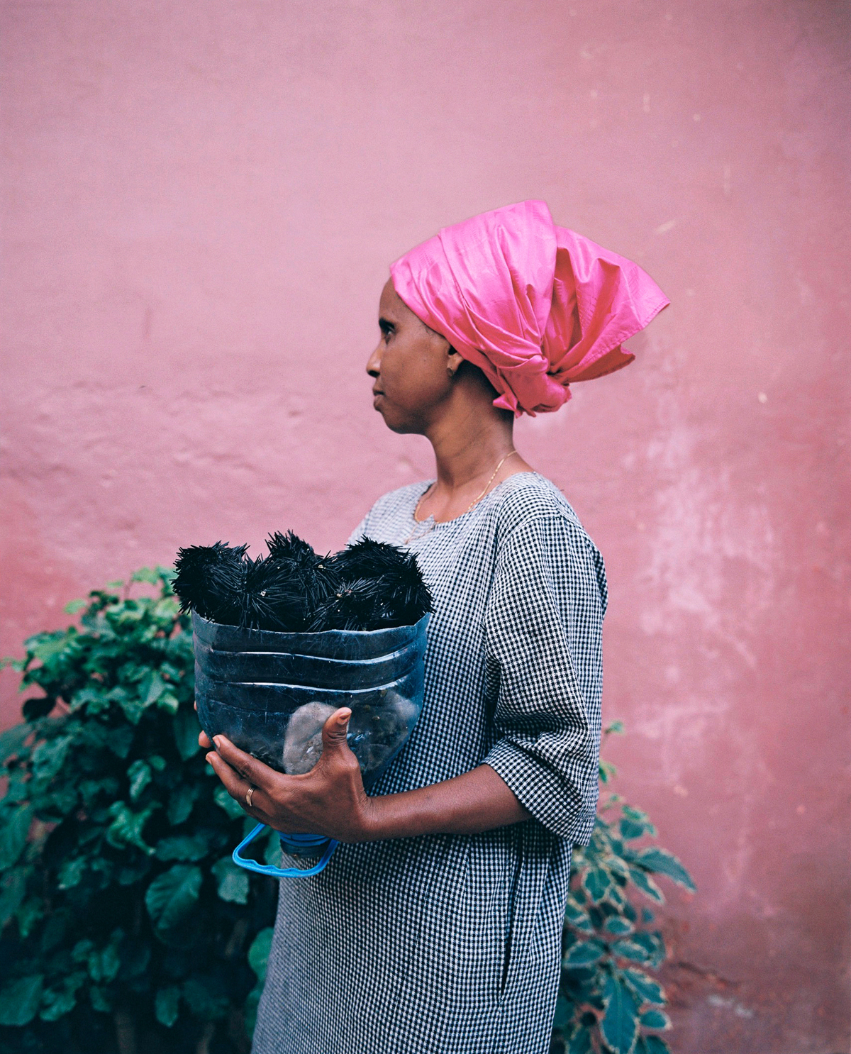 a woman with a pink headscarf standing in front of a pink wall