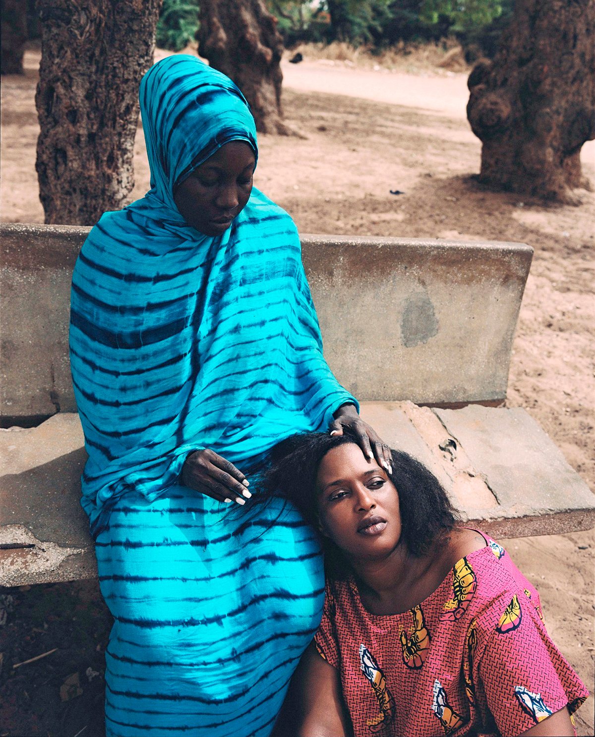 a mother holding her daughter's head in her lap outside