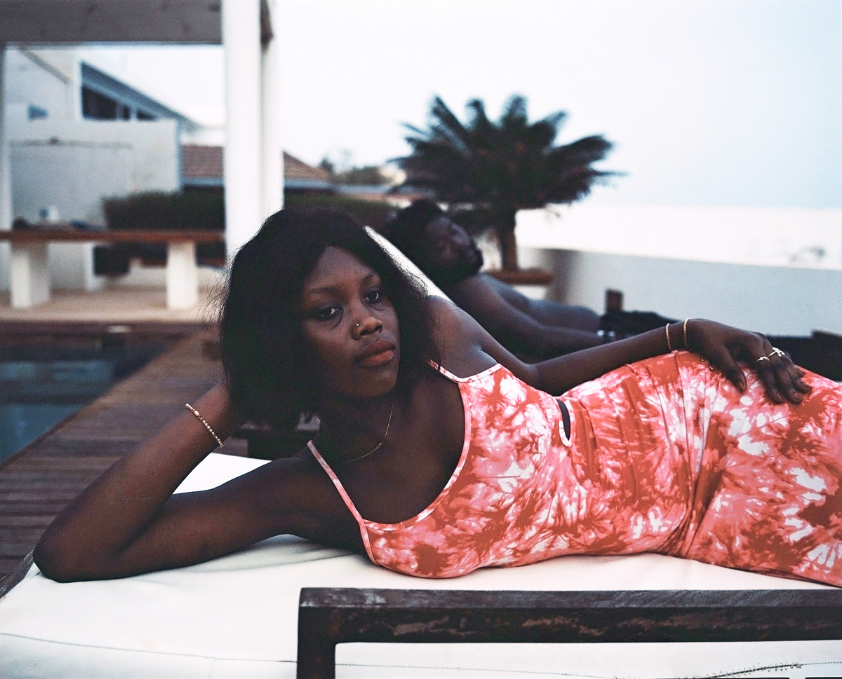 a woman lying on a lounge chair wearing a red tie dyed dress