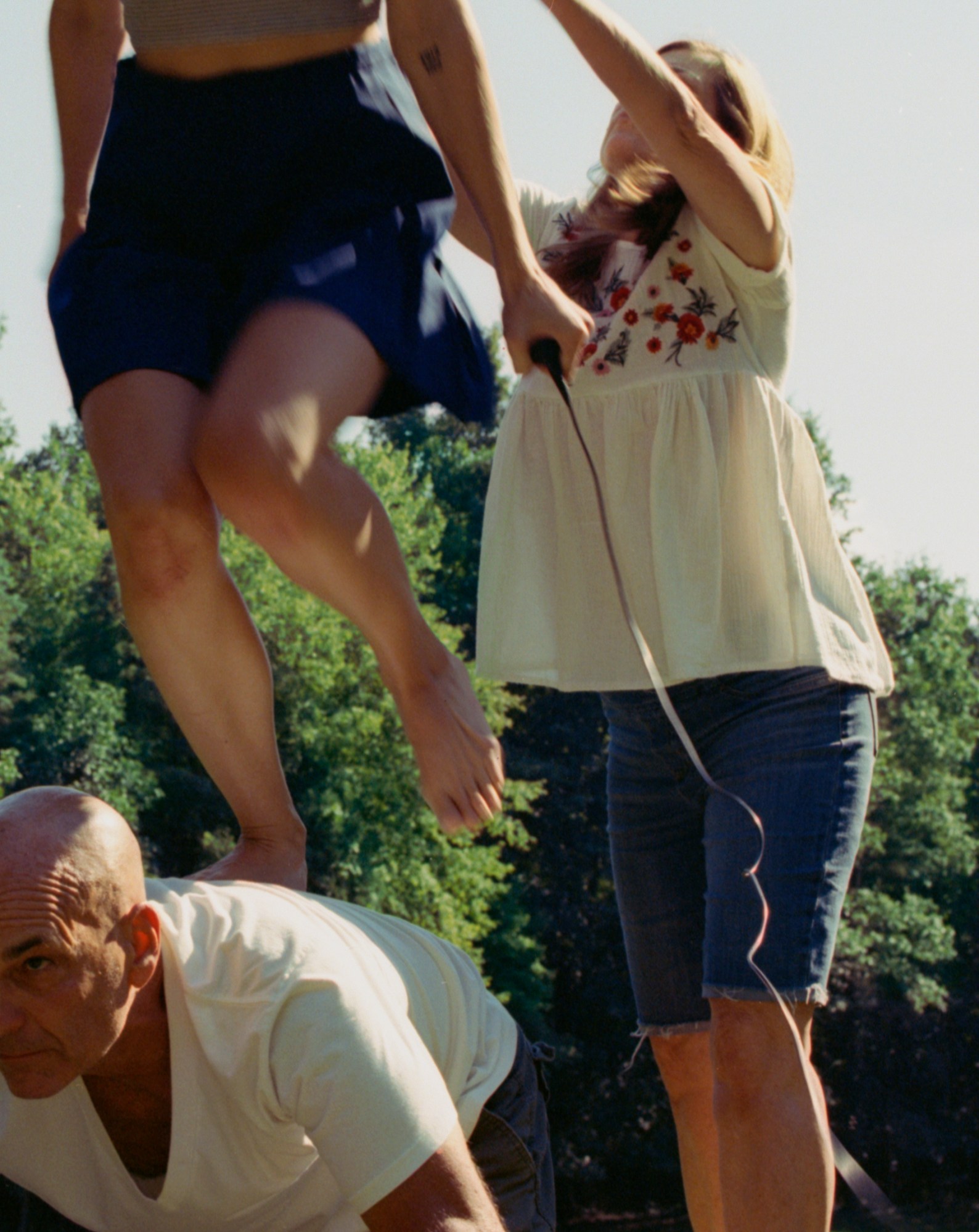 a woman stands on her step-father's back as her mother supports her