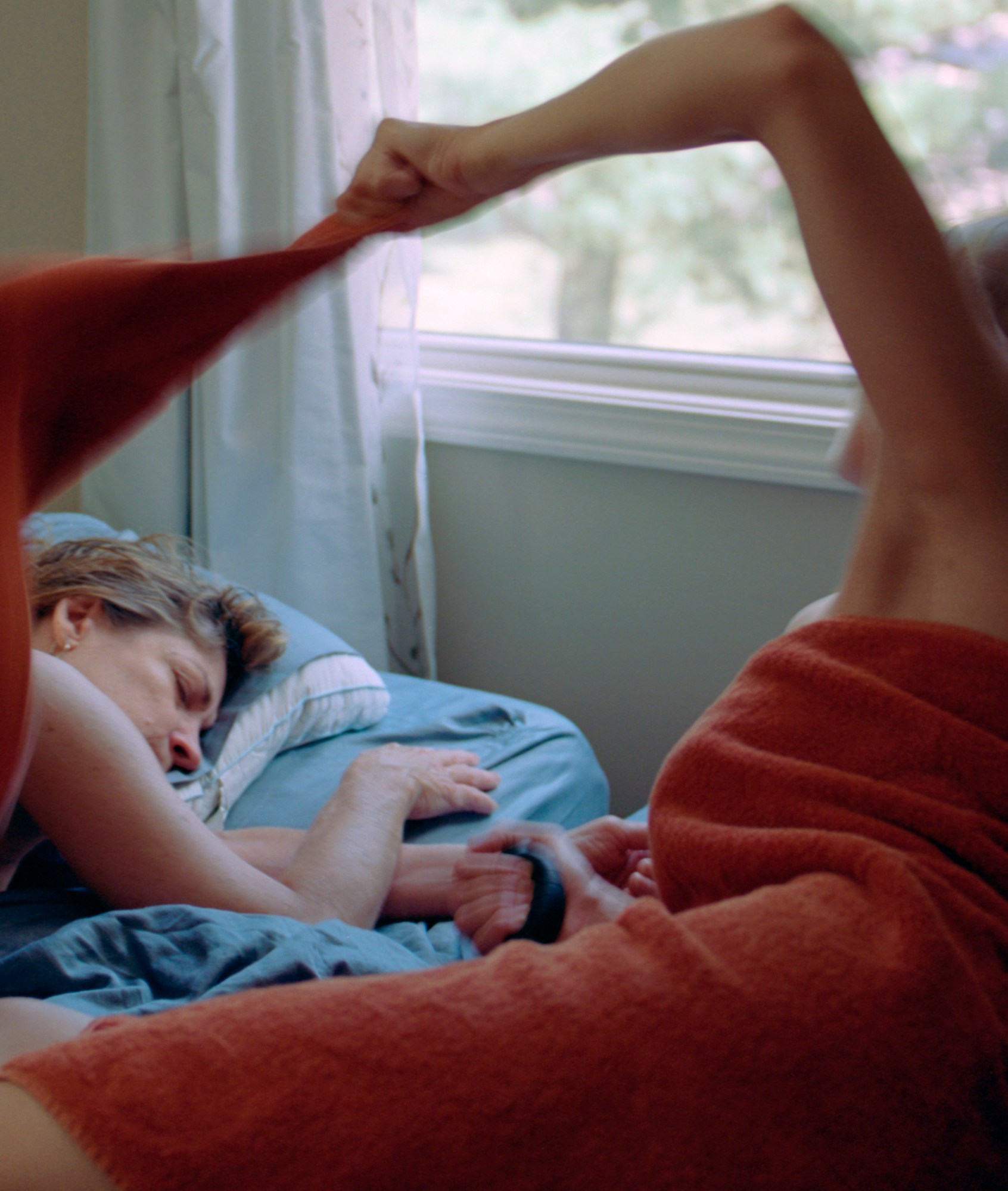 a young woman and her mother lay alongside each other in bed