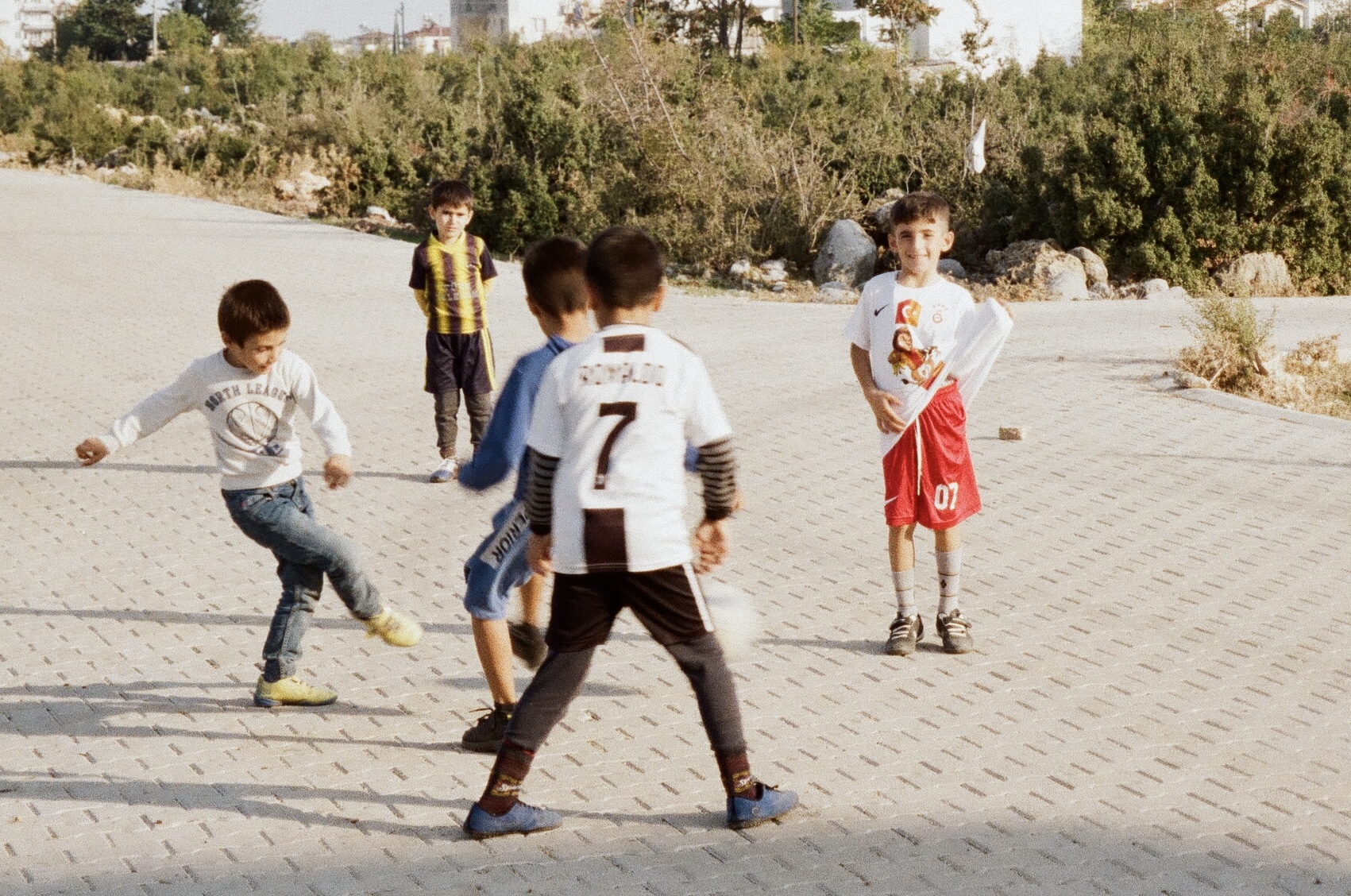 Photograph of young boys playing football on a street.