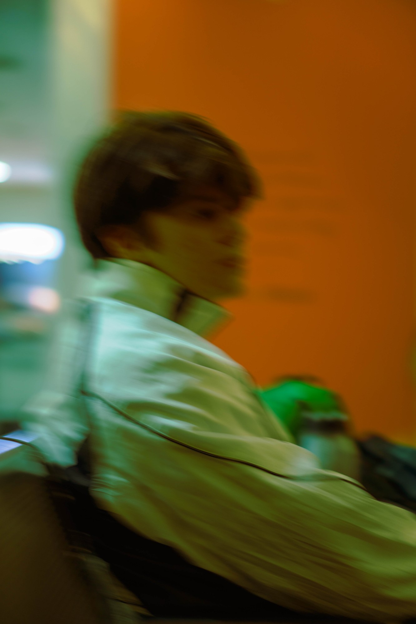 Blurry photograph of a boy in a white windbreaker sitting