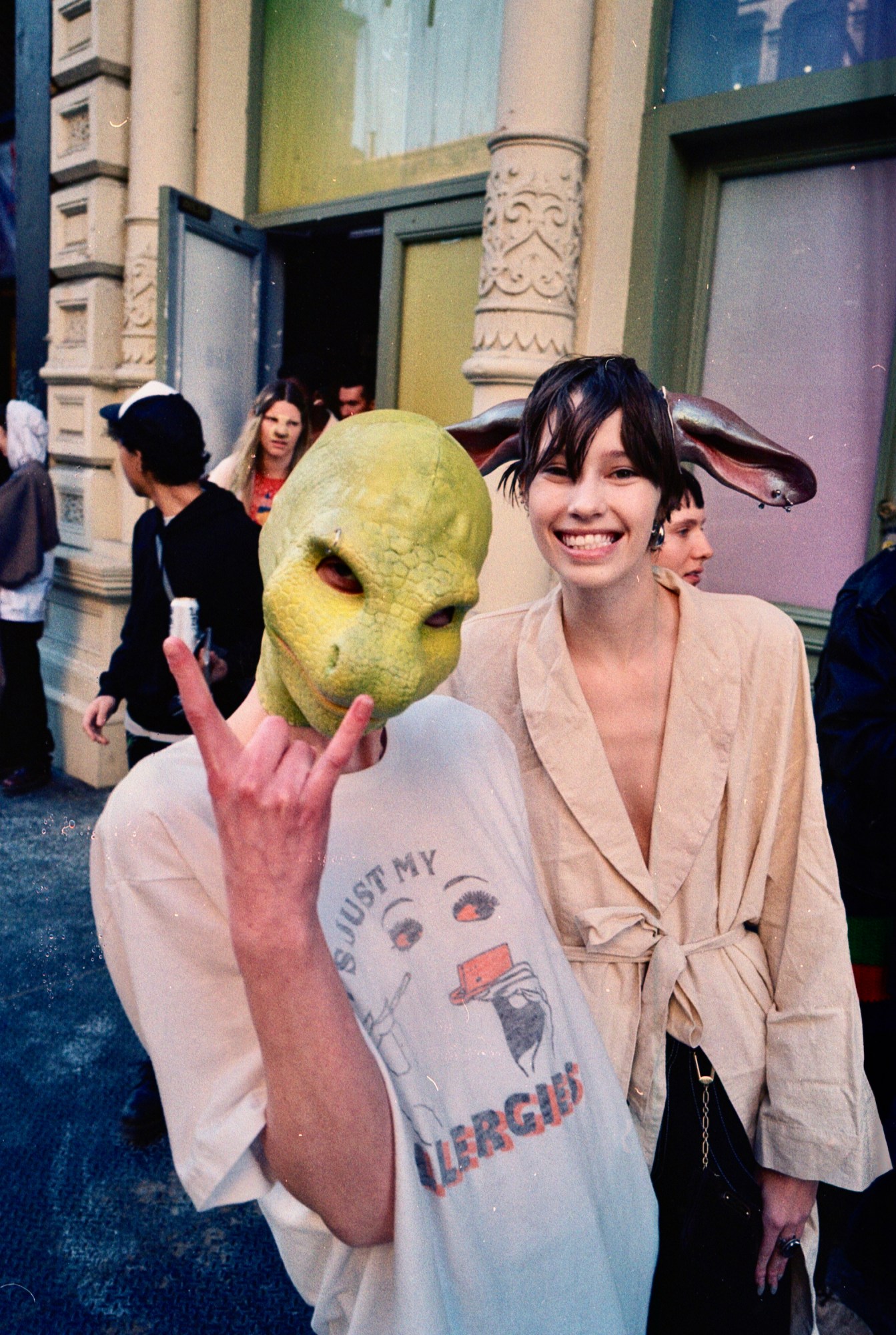 Photograph of two models coming out of the Collina Strada AW23 fashion show with their lizard and donkey prosthetics still on.