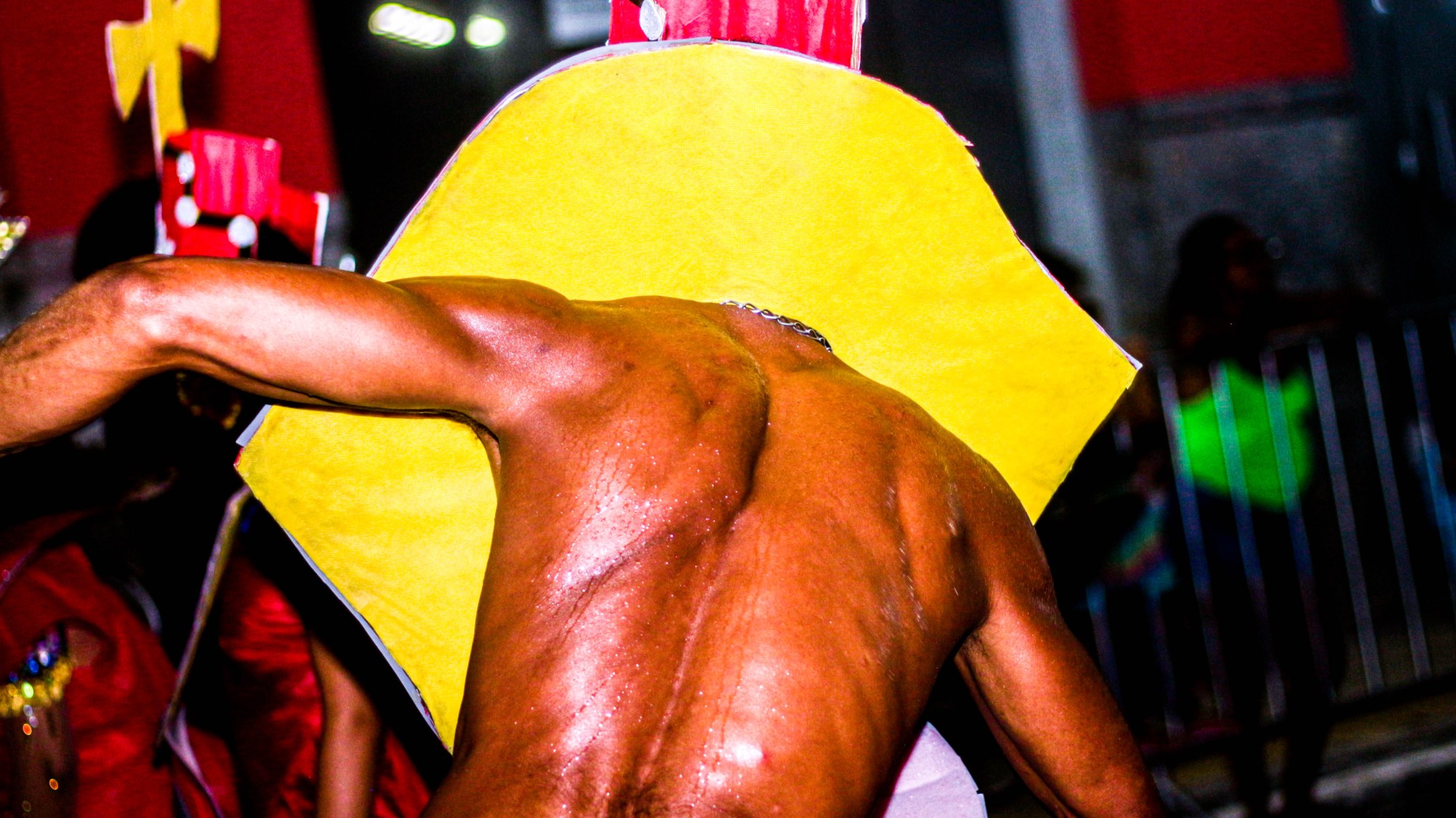 Photograph of a sweaty man from behind with his head through a yellow costume