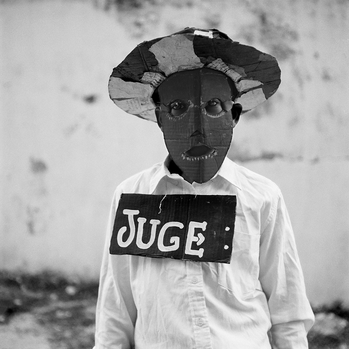 a boy wearing a mask and a sign that reads 'juge'