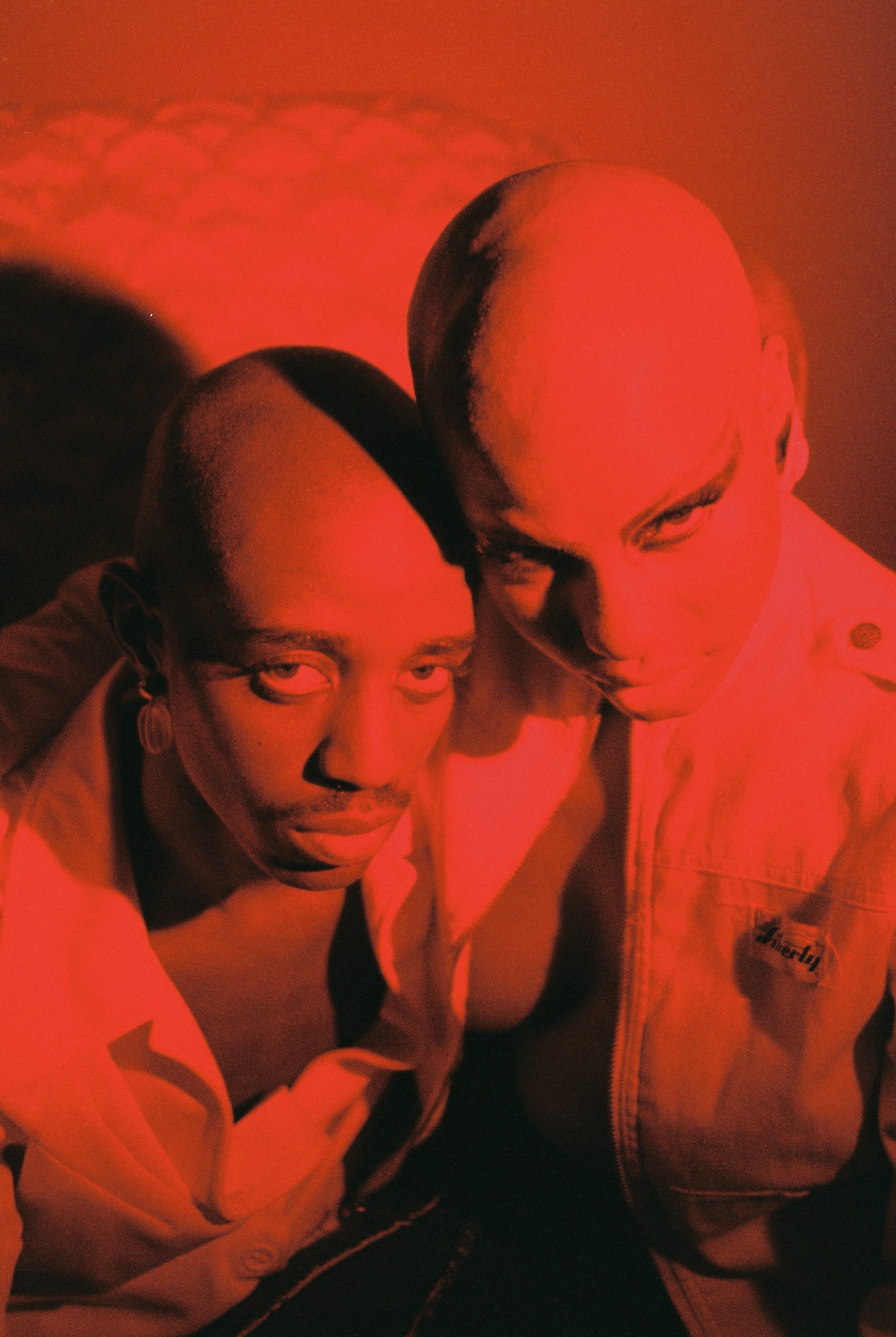 Two young people staring into the camera covered in red light.