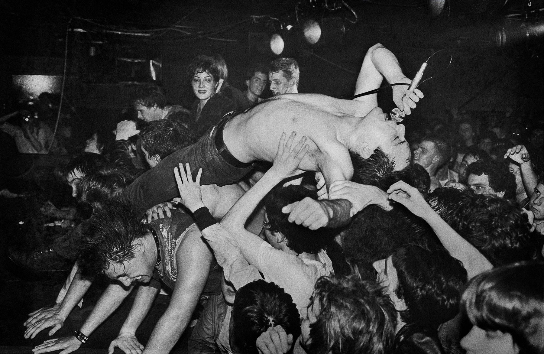 the lead singer of the dead kennedys crowdsurfs singing into a wired mic