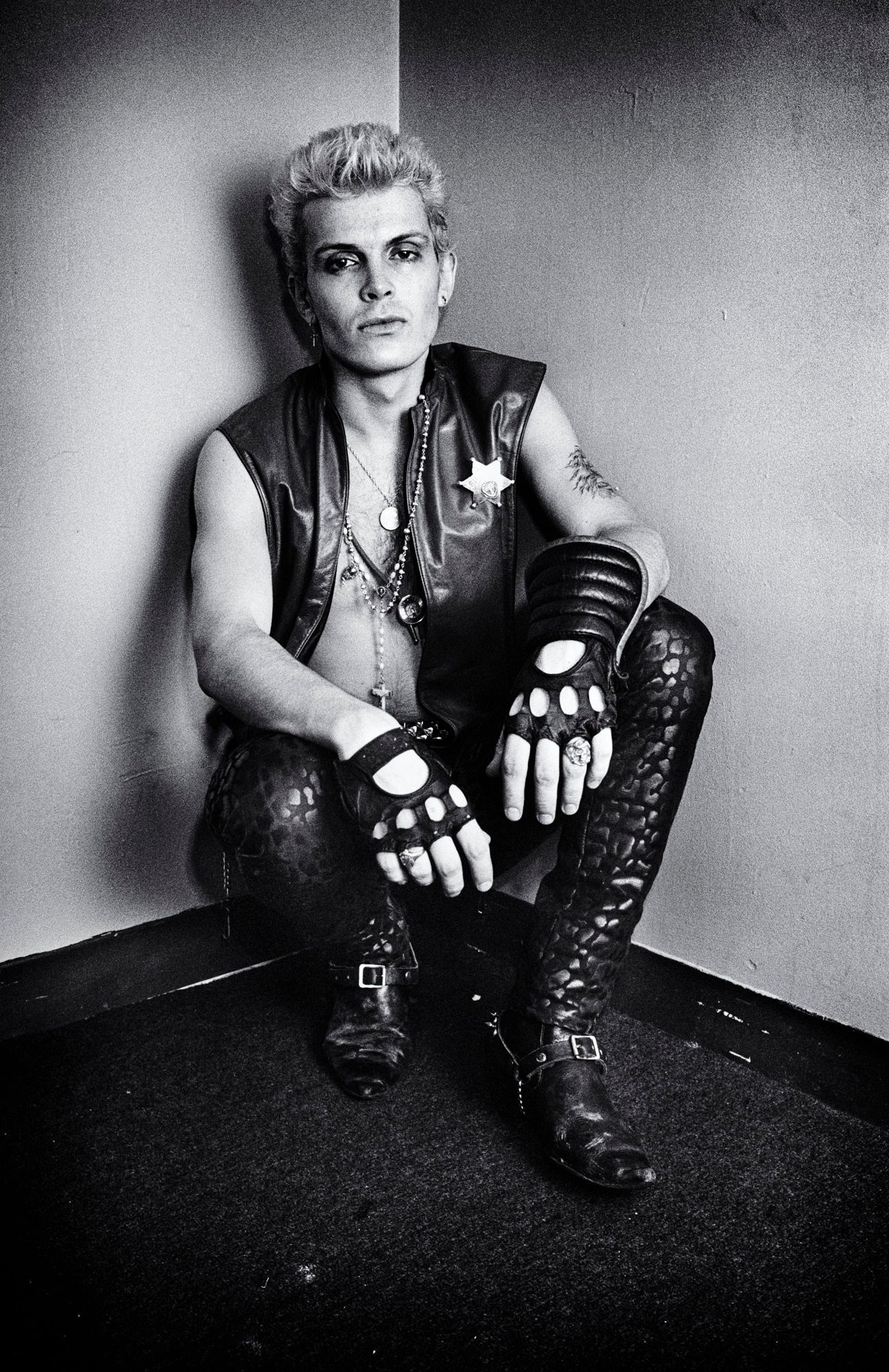 billy idol leather gloves, a vest and trousers poses for the camera