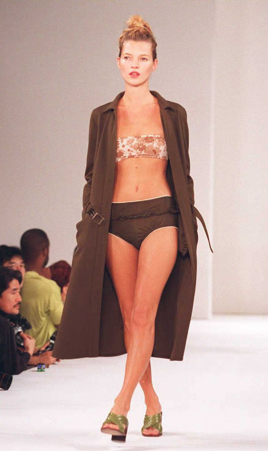 kate moss walking the miu miu runway in 1996 wearing briefs, a floral bandeau and coat