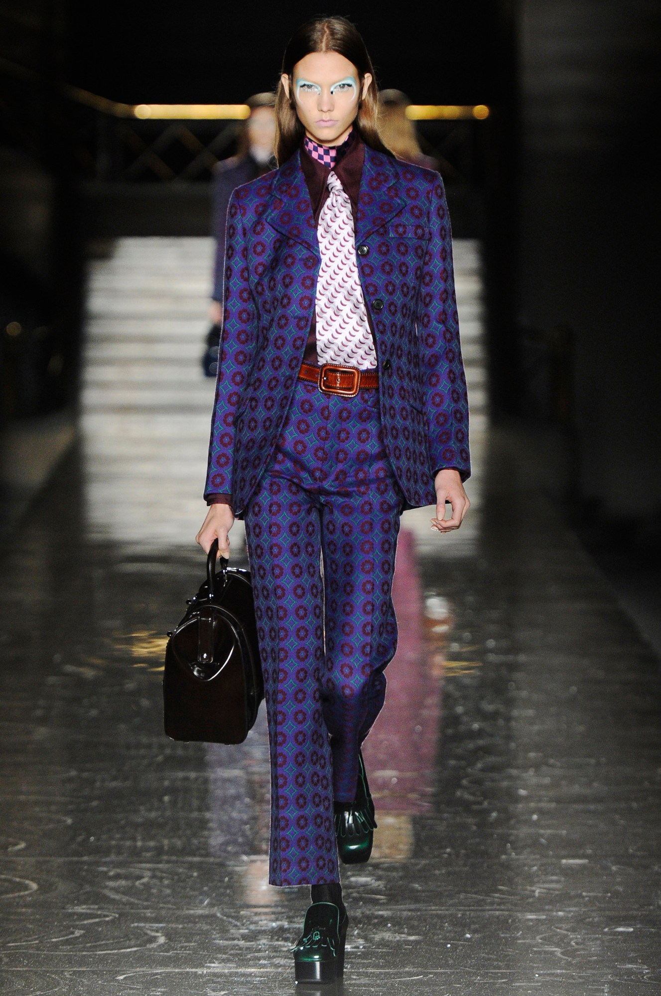 a model wearing a blue geometric tailored suit and tie on the miu miu runway 2012