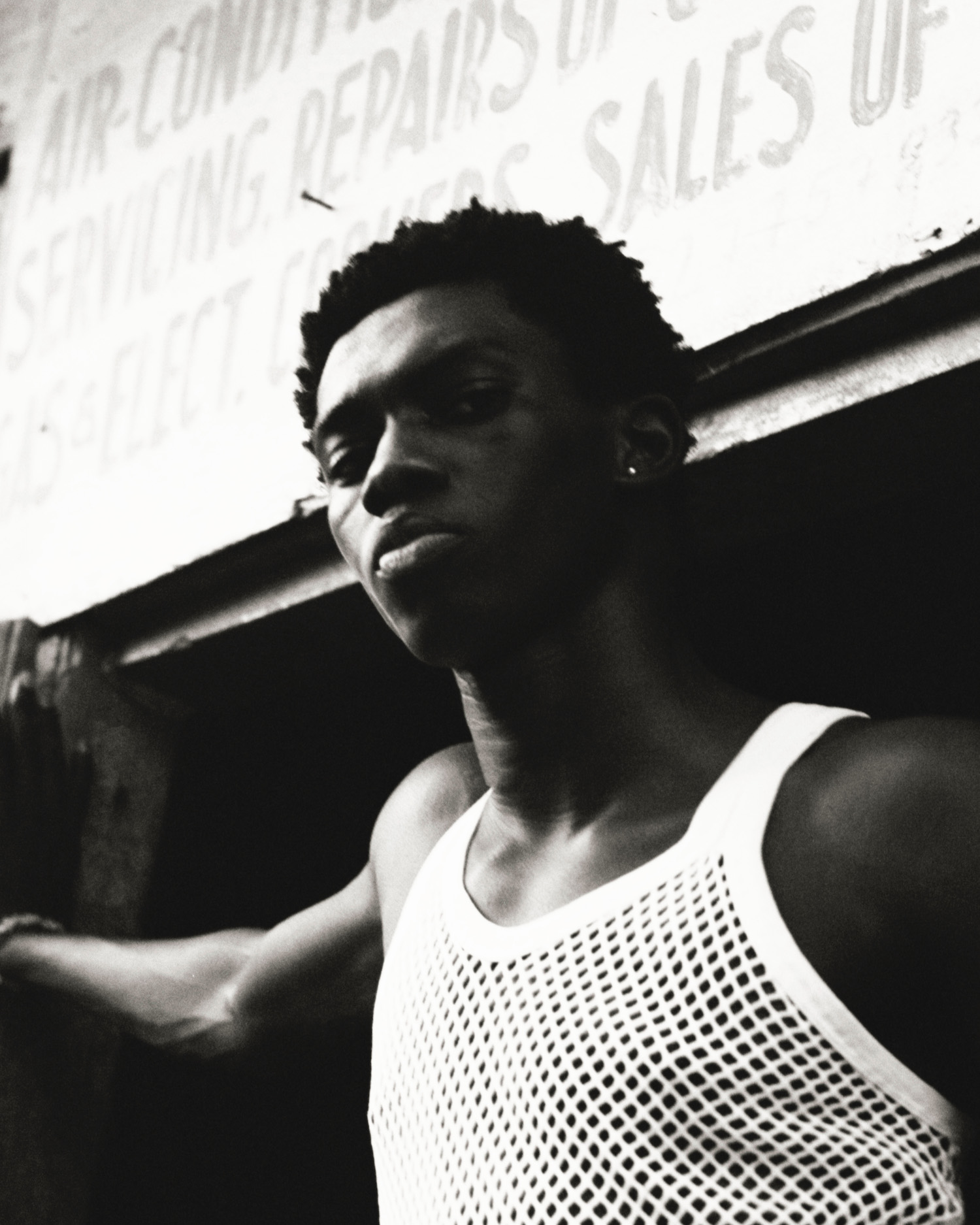 A young man in a white mesh tank top