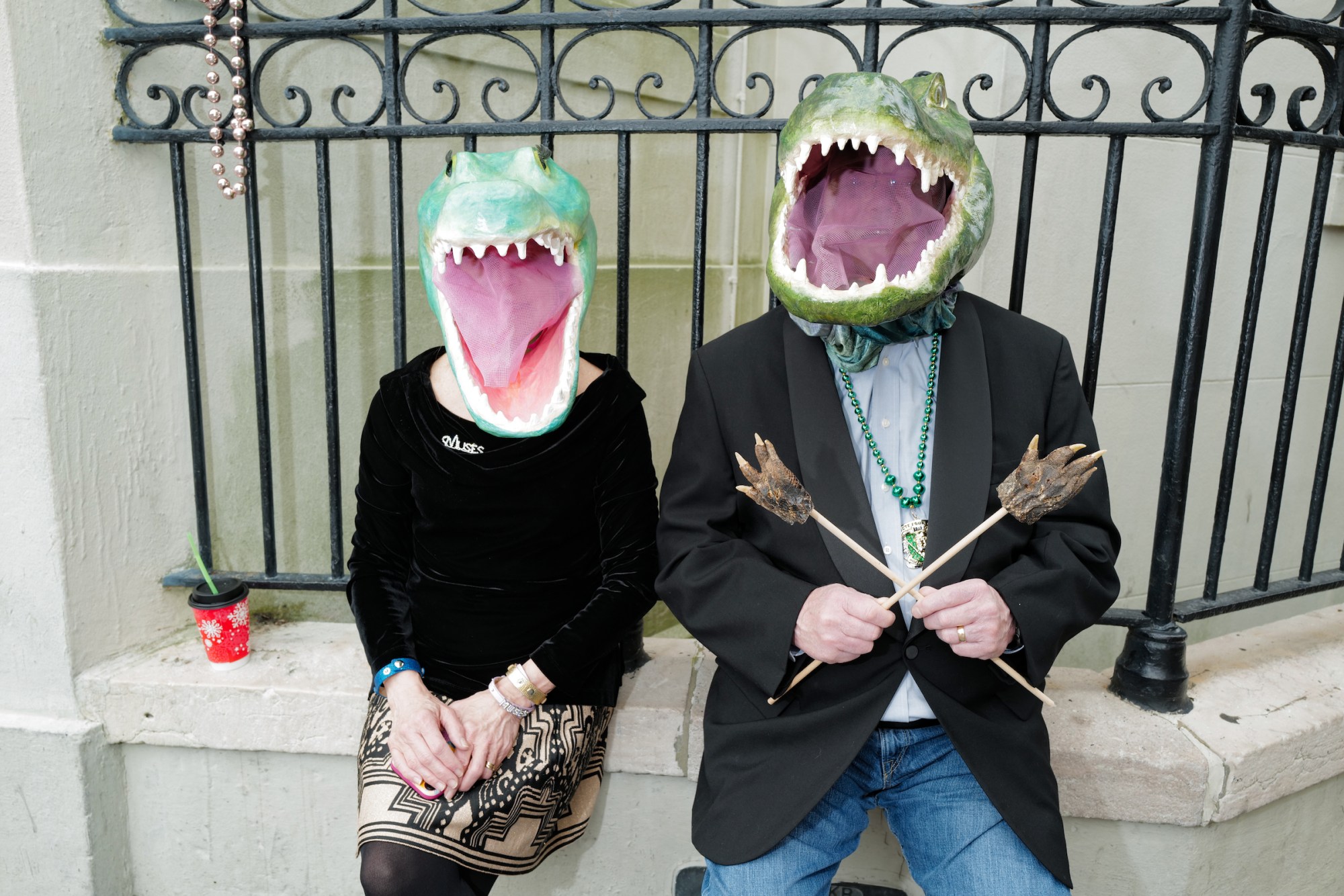 Photograph by Tom TBow Bowden of a couple sitting on a wall with crocodile masks over their faces.