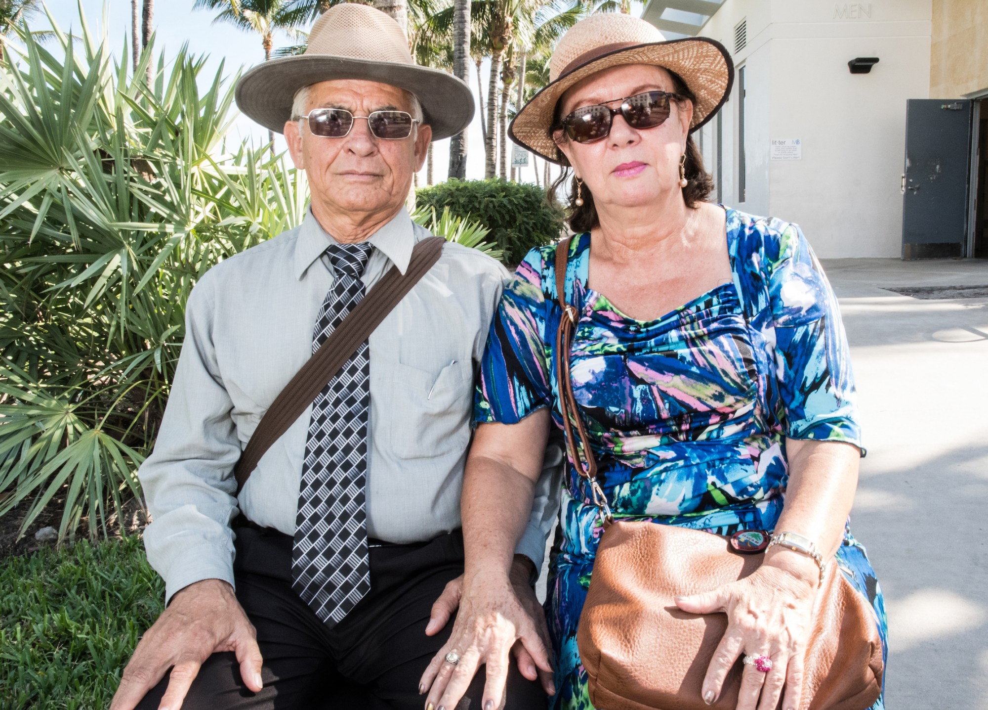 Photograph by Tom TBow Bowden of an old couple sitting outside a house the woman with her hand on the mans leg.